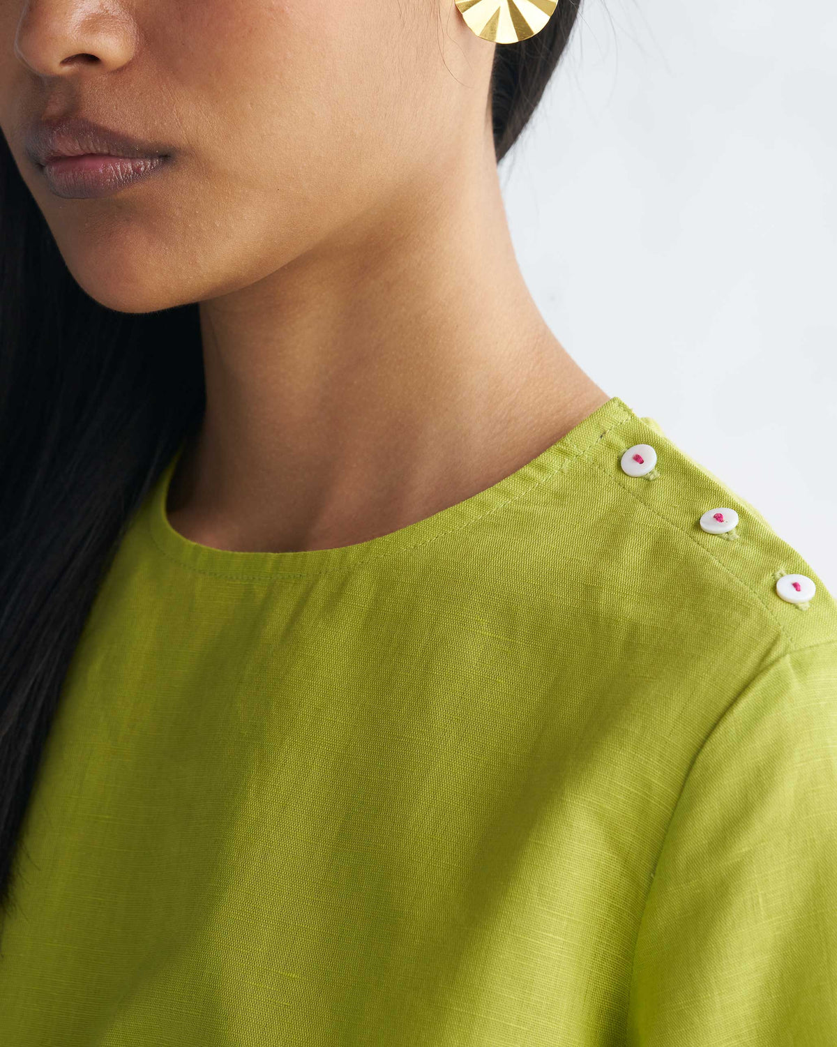 Close-up of a High slit top shoulder with three small white buttons.