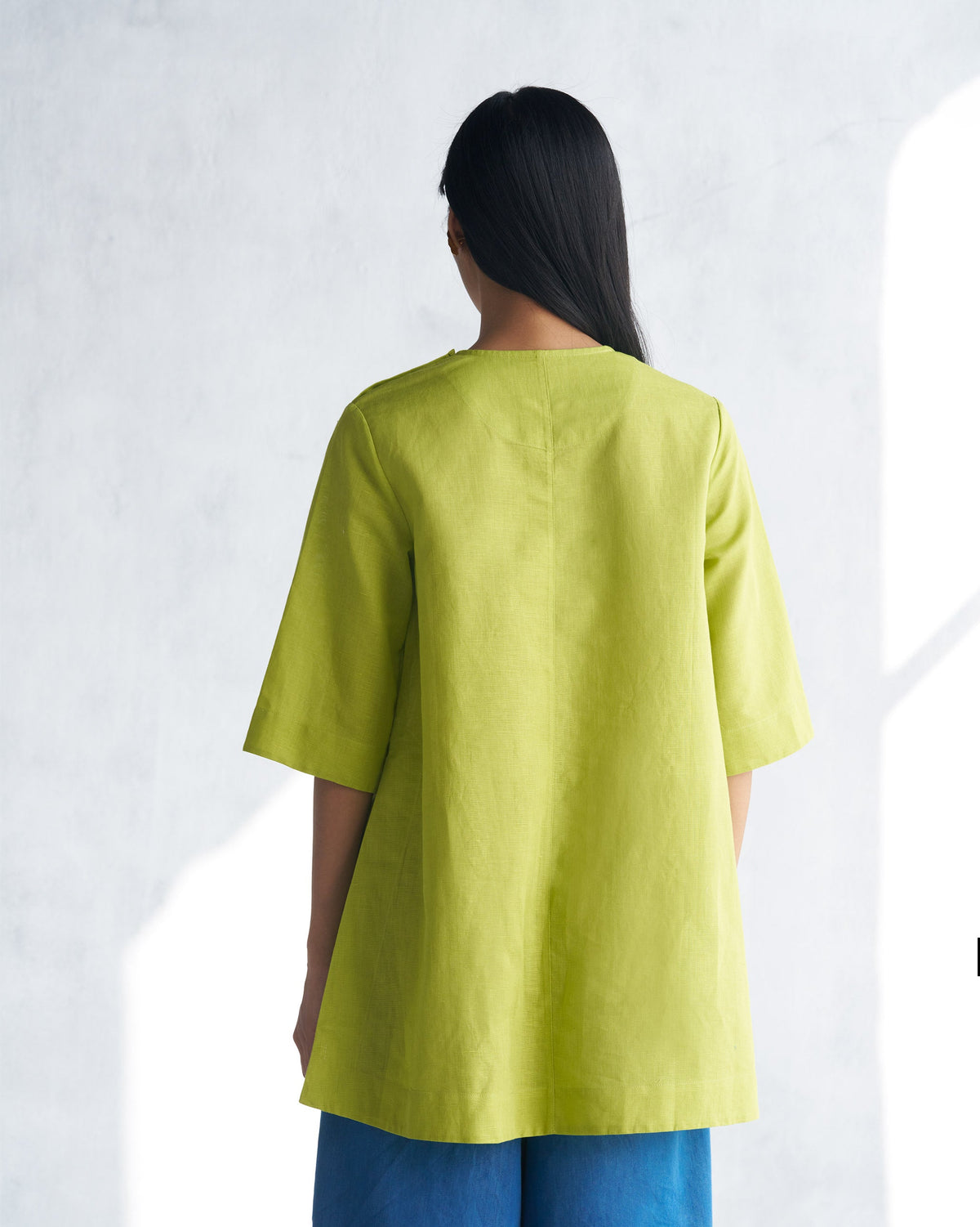 Back of a lime High slit top worn by a person.