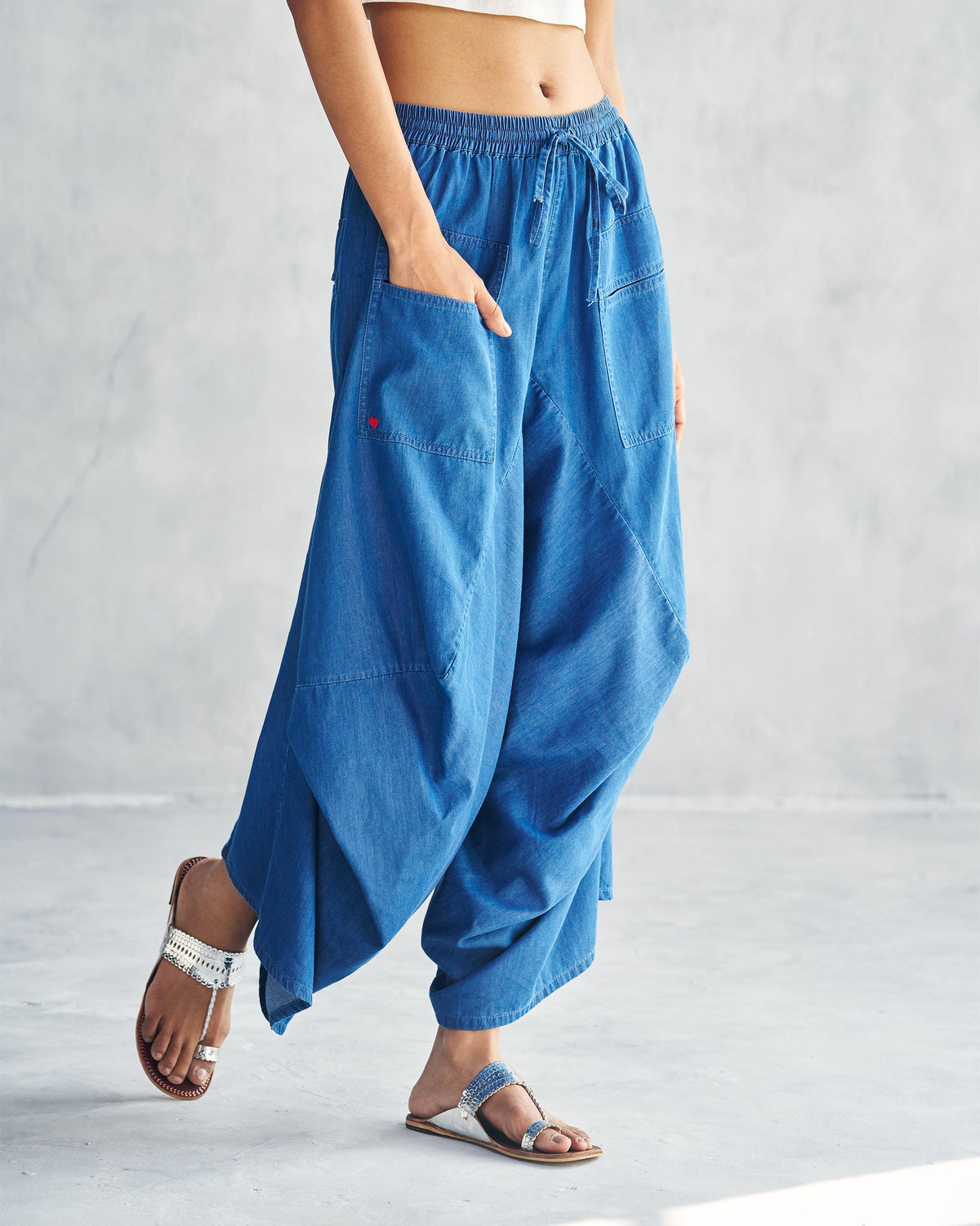 Side view of blue Yoka Trousers with a small red heart on the pocket.