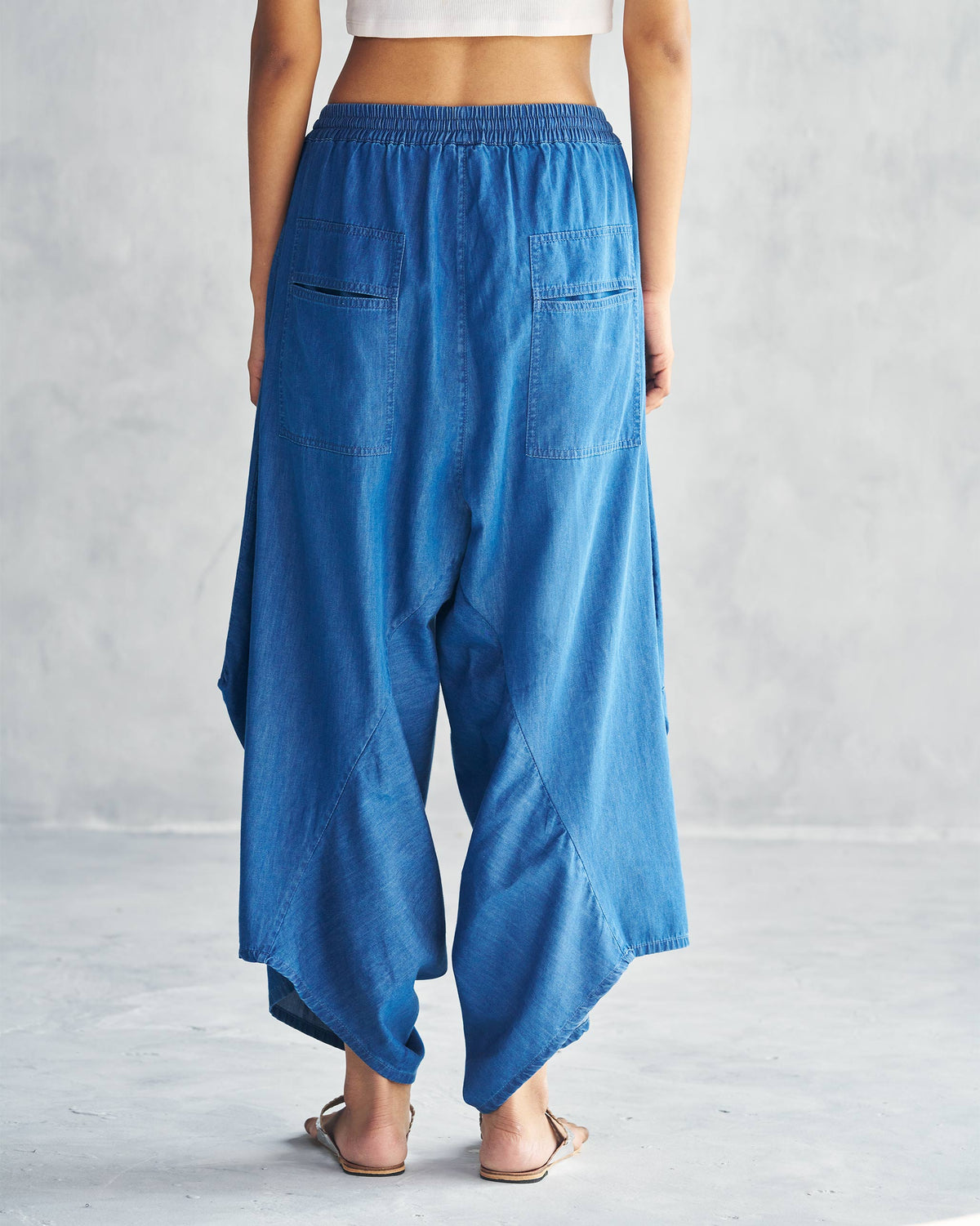 Back of blue Yoka Trousers with welt pockets worn by a person.