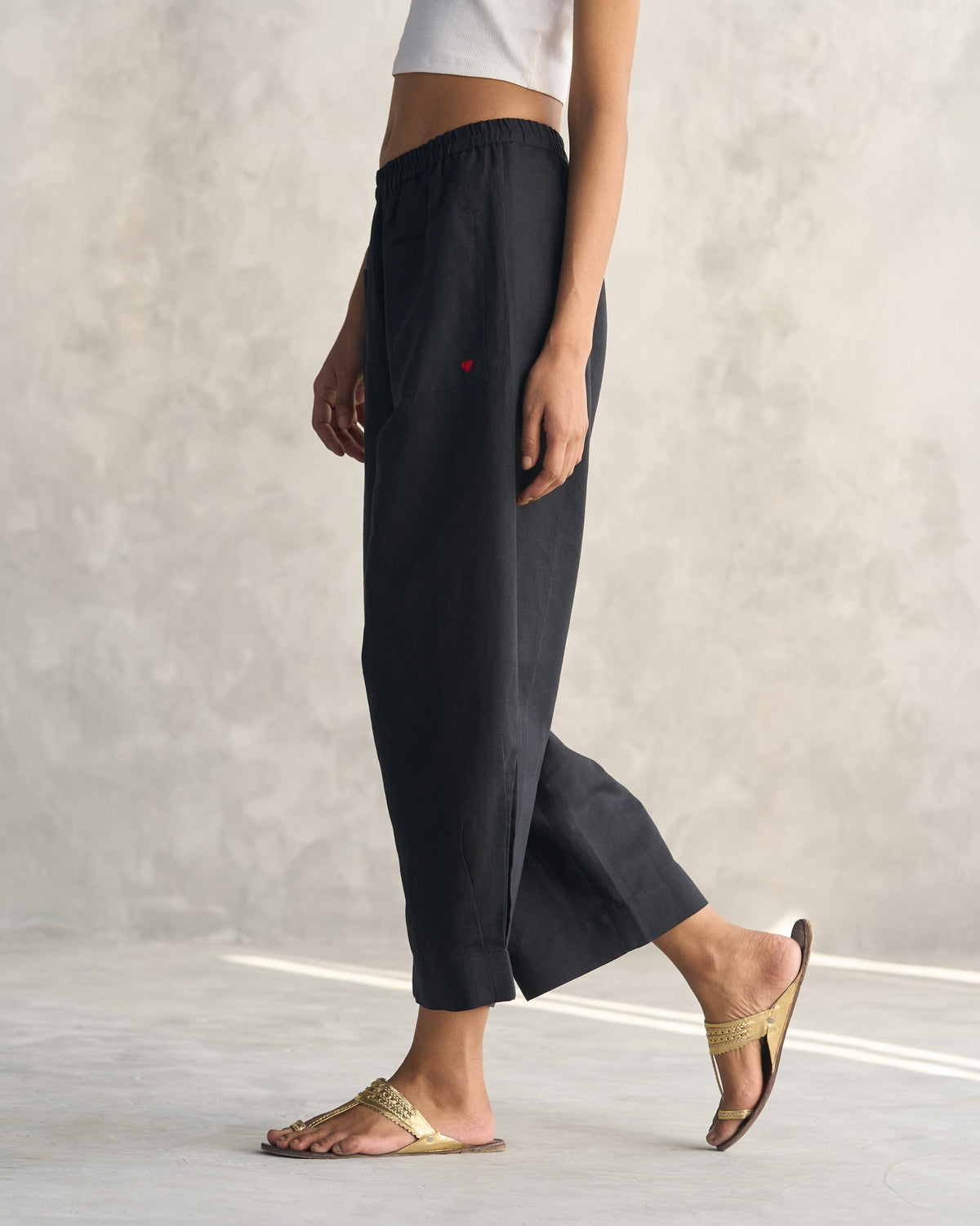 Side view of black Serene pants with a small red heart near the hip.
