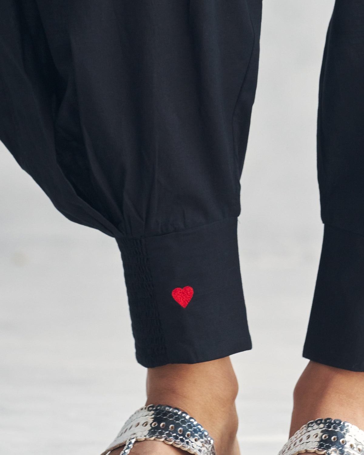 Close-up of a black Puff Pants cuff showing red heart embroidery.