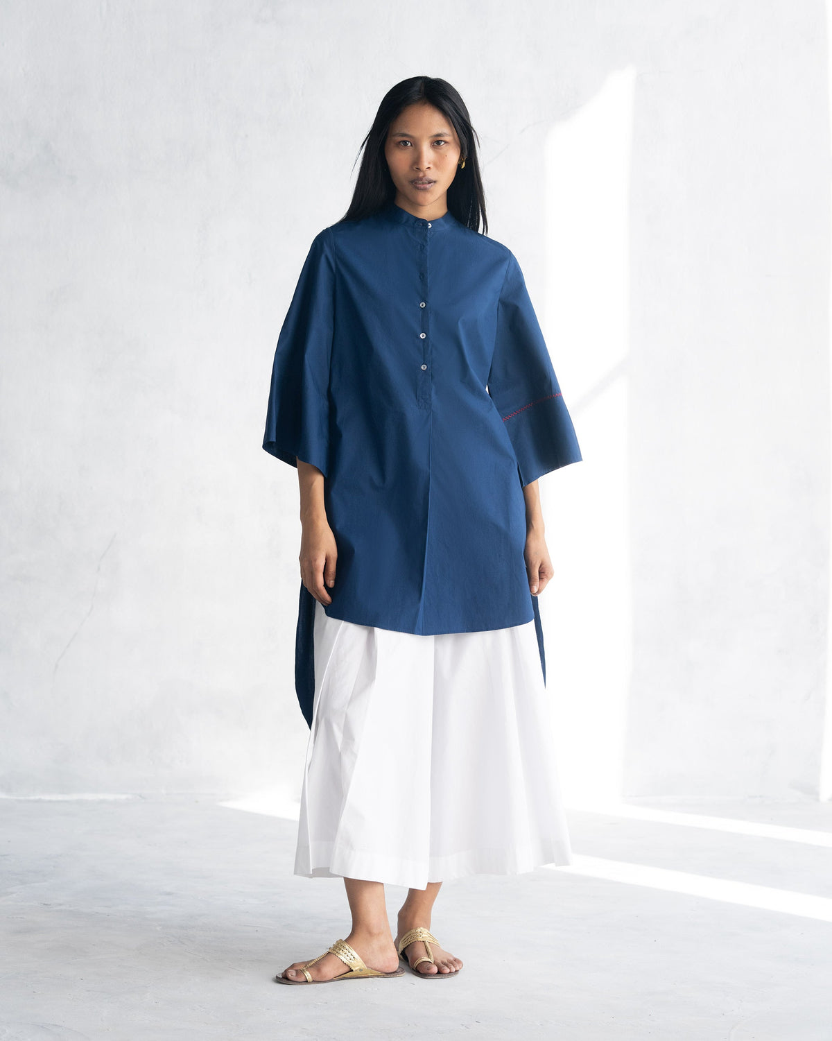 Person wearing an indigo Pema Top with a band collar and button placket.