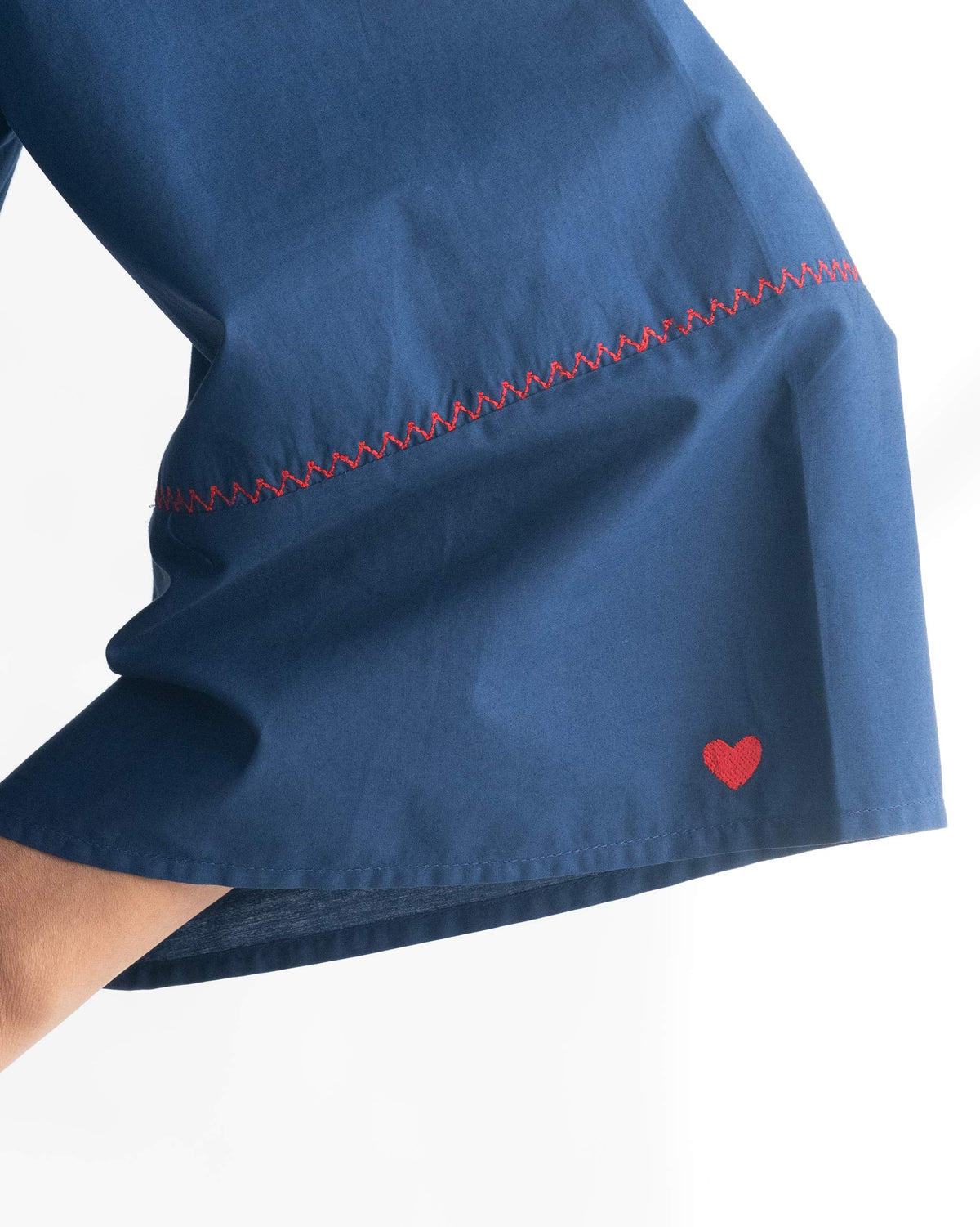 Close-up of an indigo Pema Top hem with red zigzag stitching and a red heart.