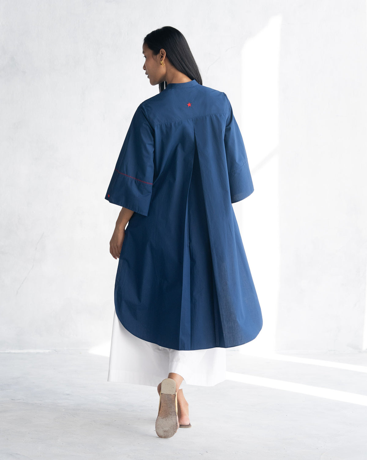 Back of an indigo Pema Top worn by a person, with a small red star at the collar.