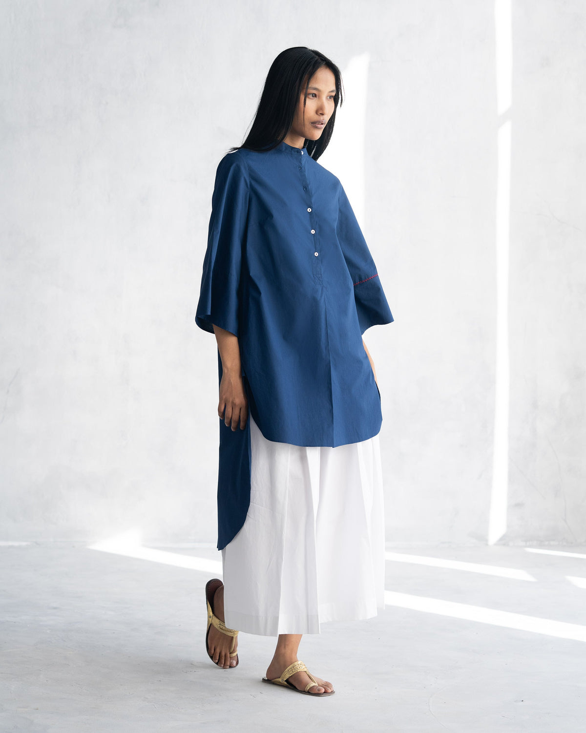 Side view of an indigo Pema Top with its curved high-low hem.
