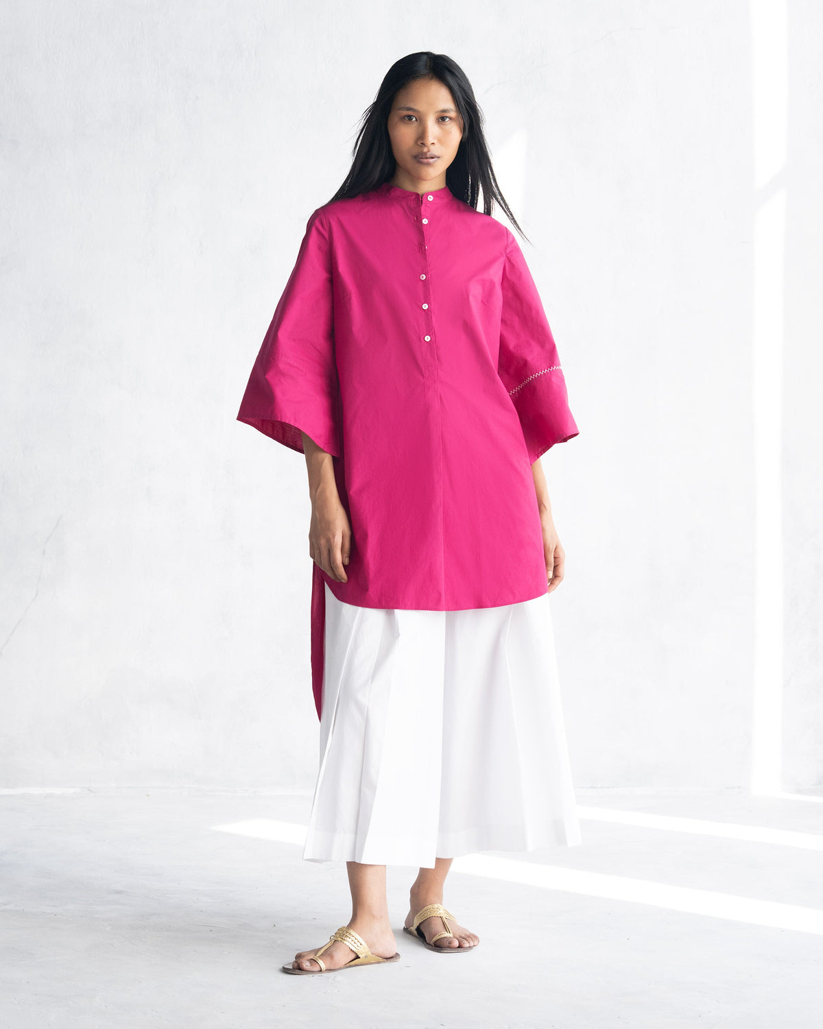 Person wearing a berry Pema Top with a band collar and button placket.