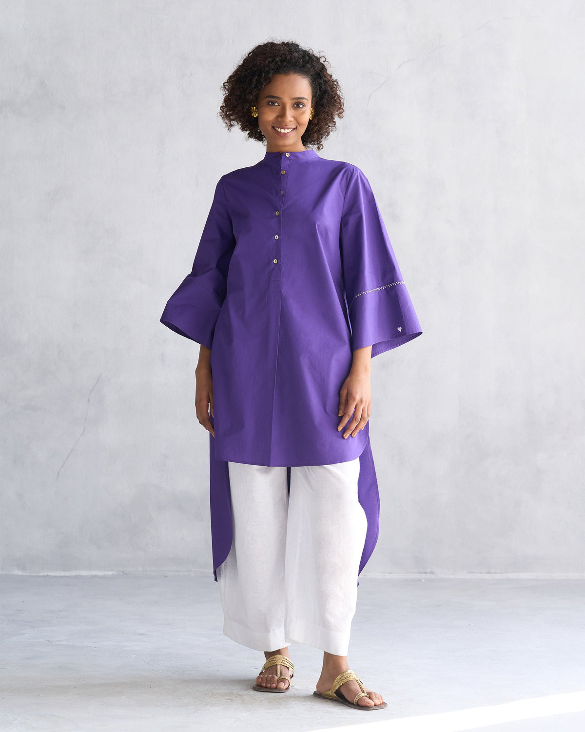Person wearing a purple Pema top with a band collar and flared sleeves.