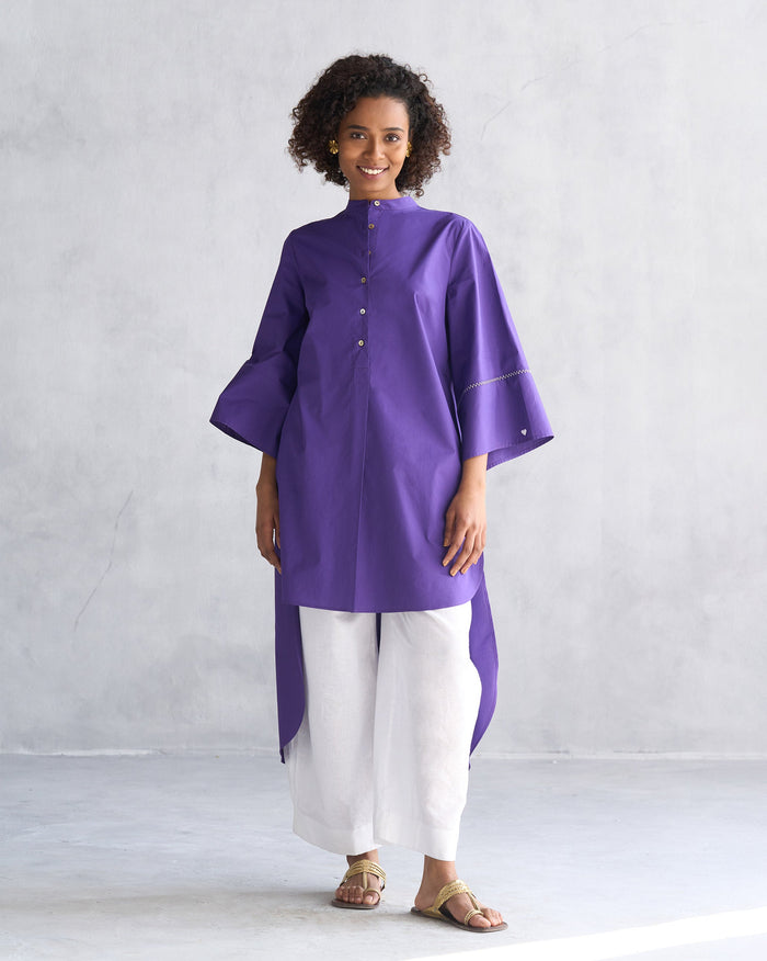 Person wearing a purple Pema top with a band collar and flared sleeves.