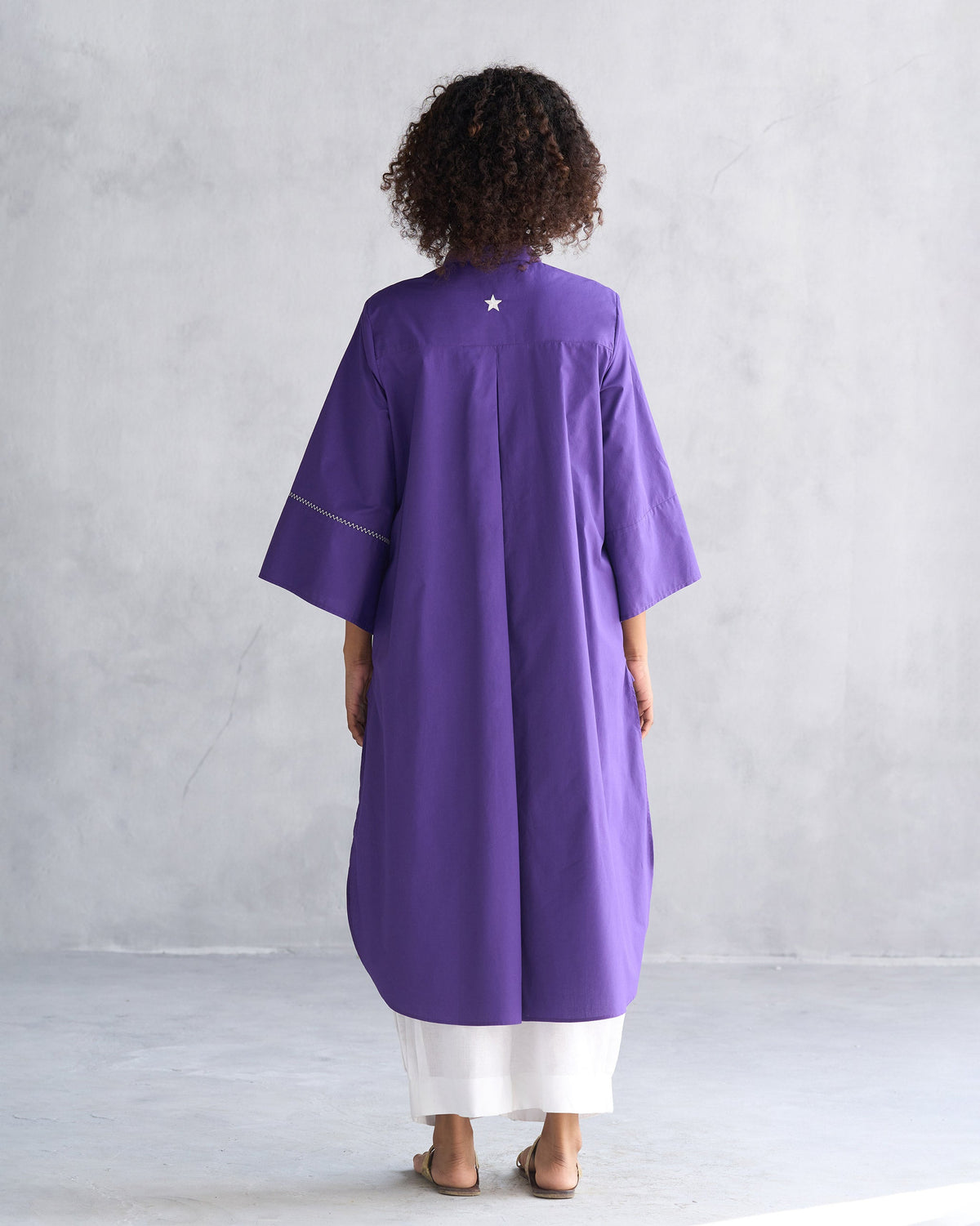 Full-length back of a purple Pema top with a longer back hem worn by a person.