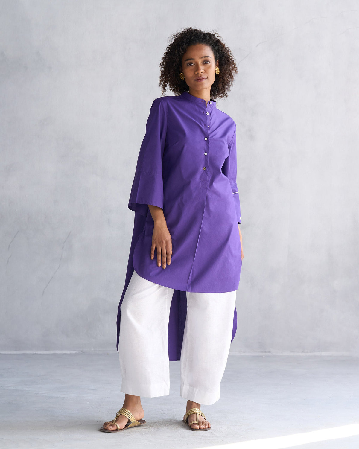 Person wearing a purple Pema top with a band collar and a high-low hem.