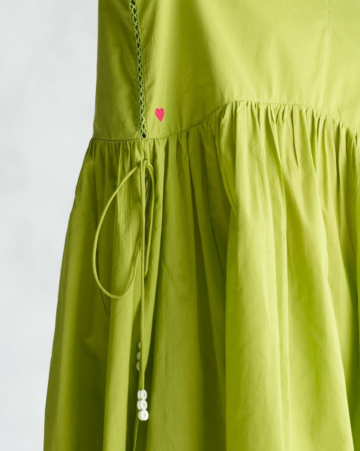 Close-up of a lime waist gathered kurta showing a pink heart and drawstring tie.