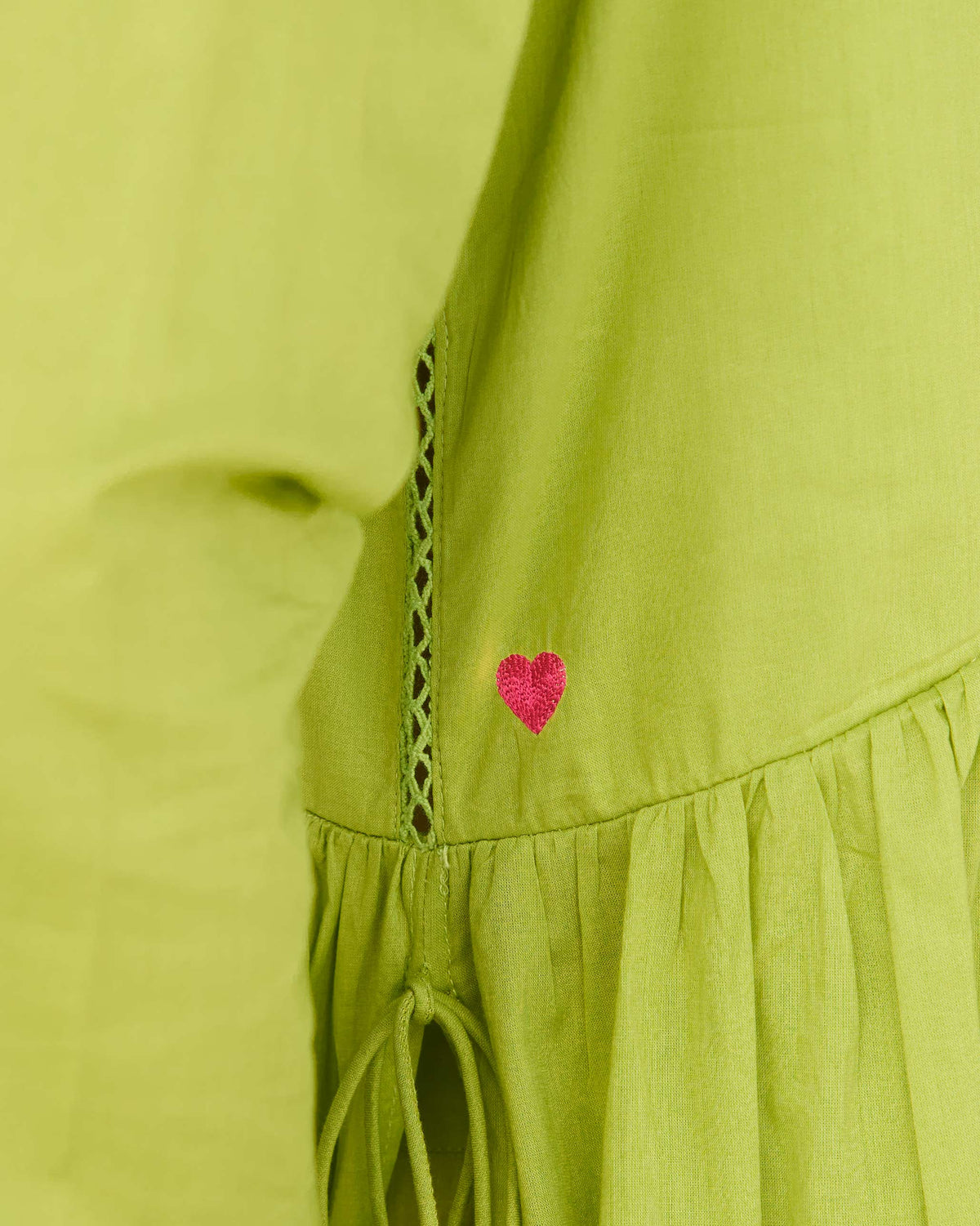 Close-up of a lime kurta's side seam with lattice trim and a gathered hem.