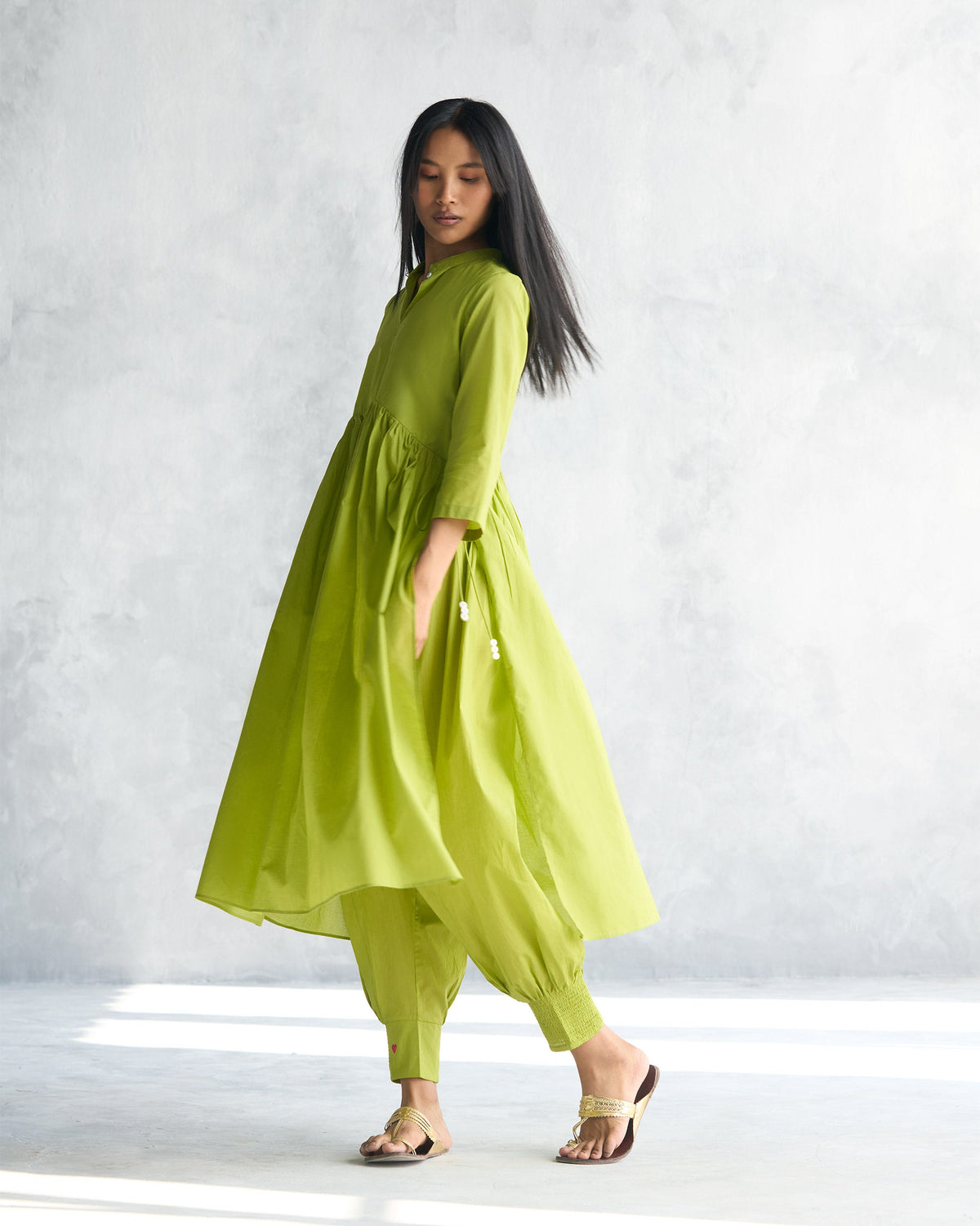 Side view of a lime waist gathered kurta with tasselled ties at the side.