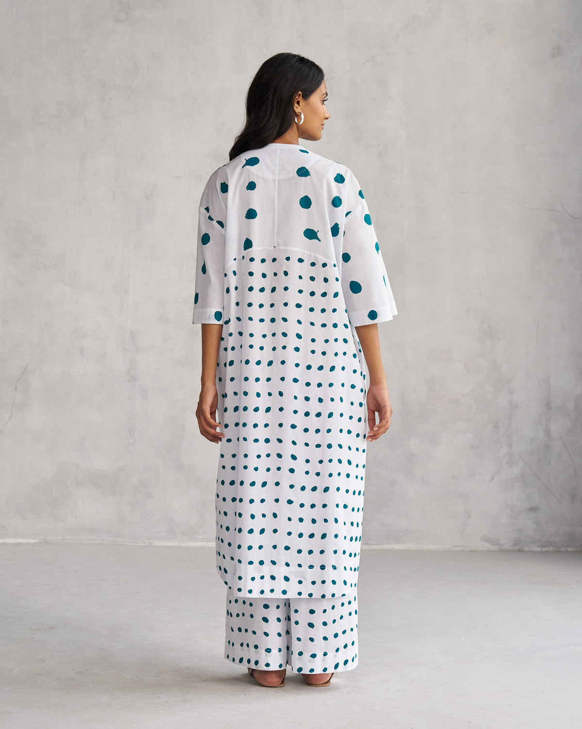 Back of a white Boba panelled kurta with teal dots worn by a person.