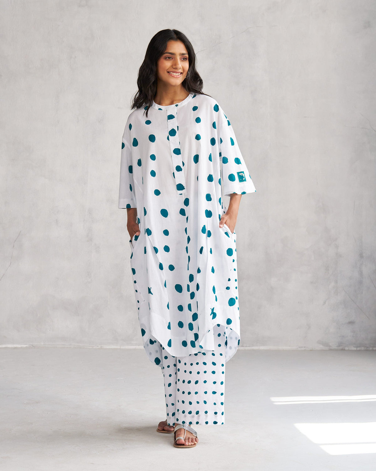 Person wearing a white Boba panelled kurta with teal dots and side pockets.