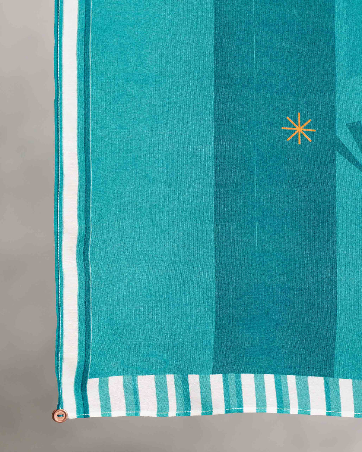 Close-up of a teal Pacific Scarf corner showing a striped border and gold starburst.