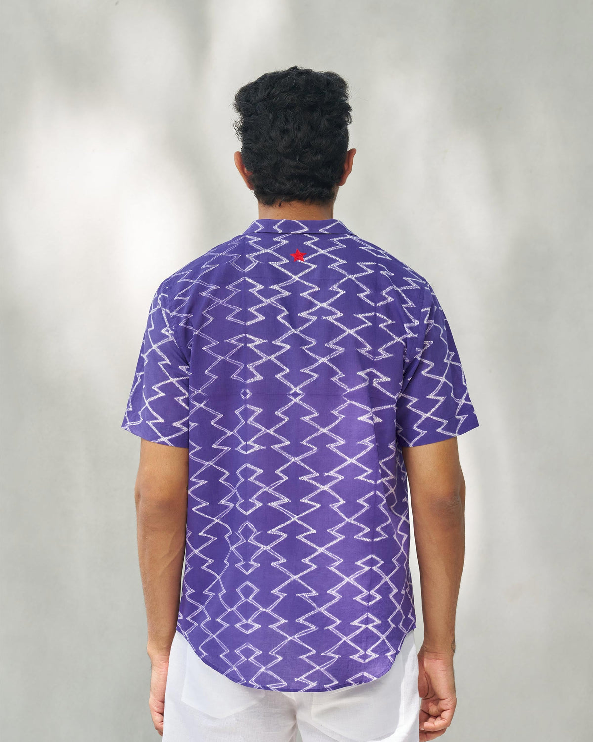 Back of a purple Riverine shirt worn by a person, with a small red star at the upper back.