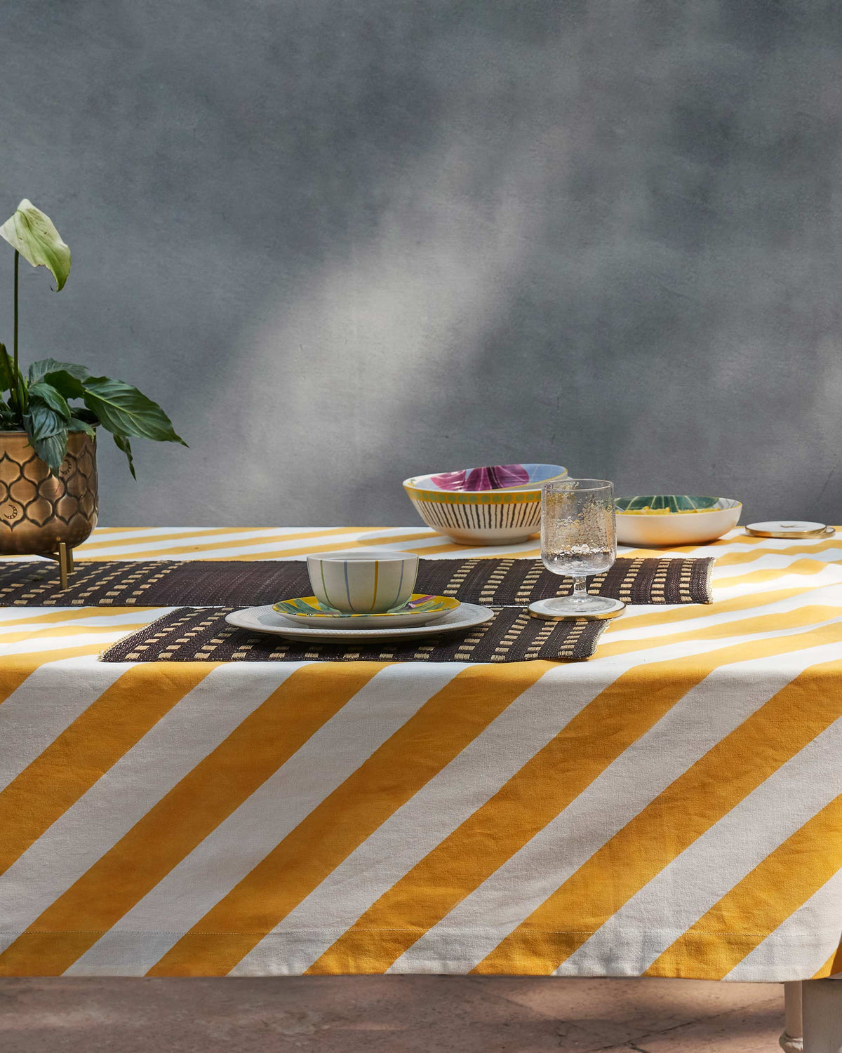 Zanzibar Table Cloth Small covering a dining table in yellow and white stripes.