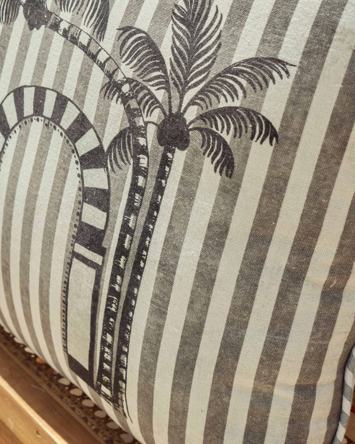 Close-up of a Mario cushion cover in grey stripes with a palm tree and arch.