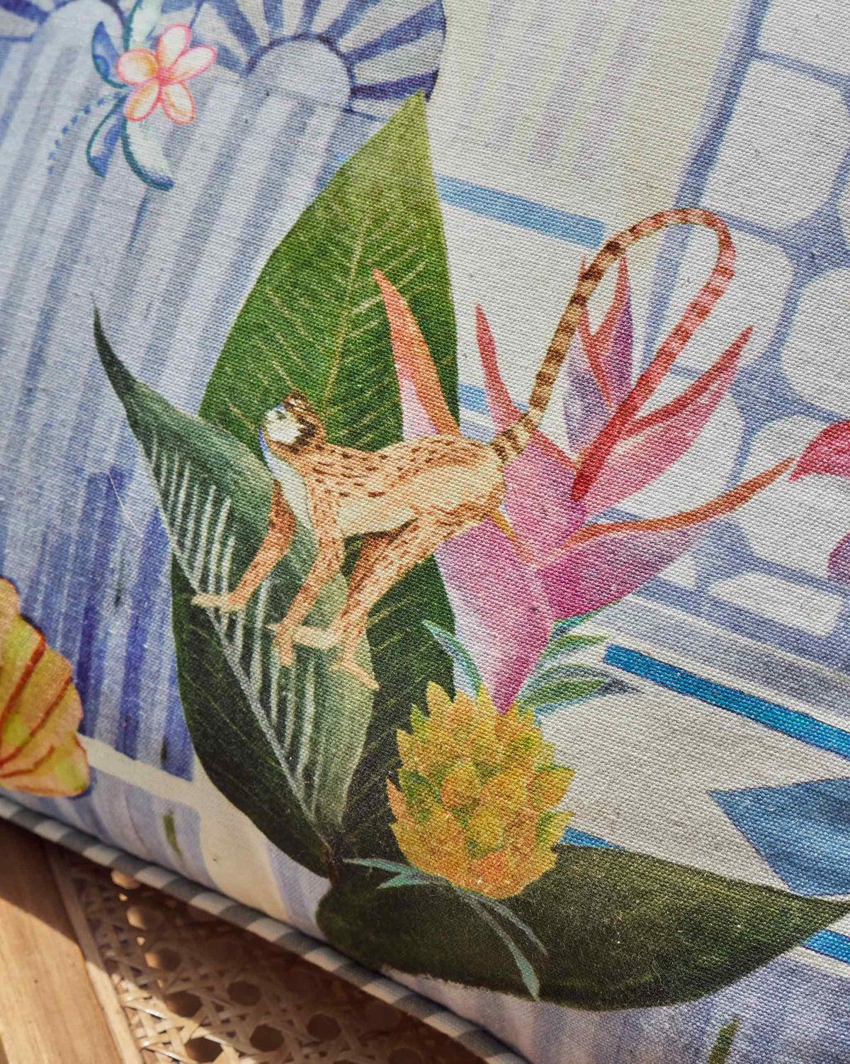 Close-up of a blue Mario cushion cover with a monkey and tropical leaves.
