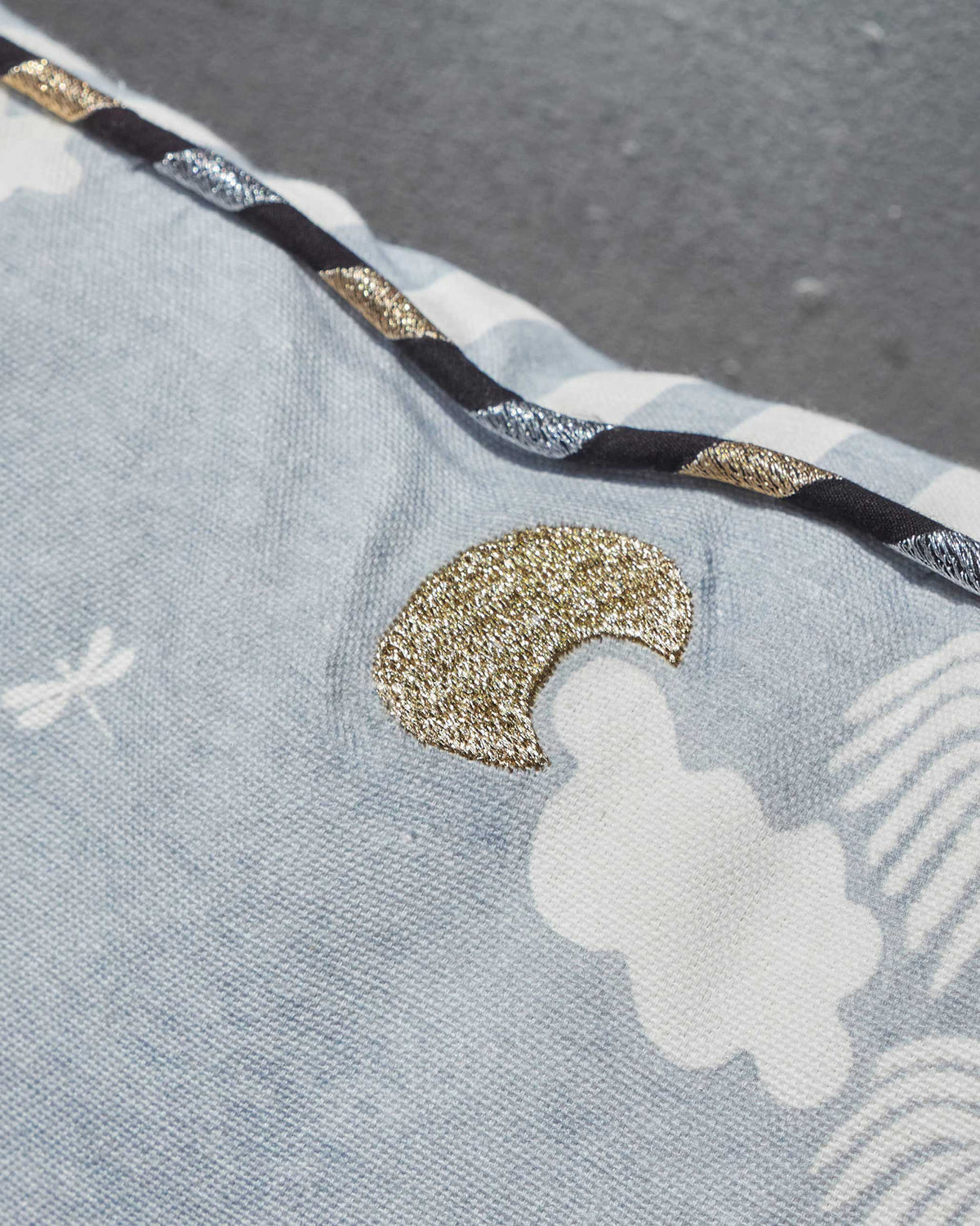 Close-up of a Coastal Evening Cushion Cover showing a gold moon and clouds on pale blue.