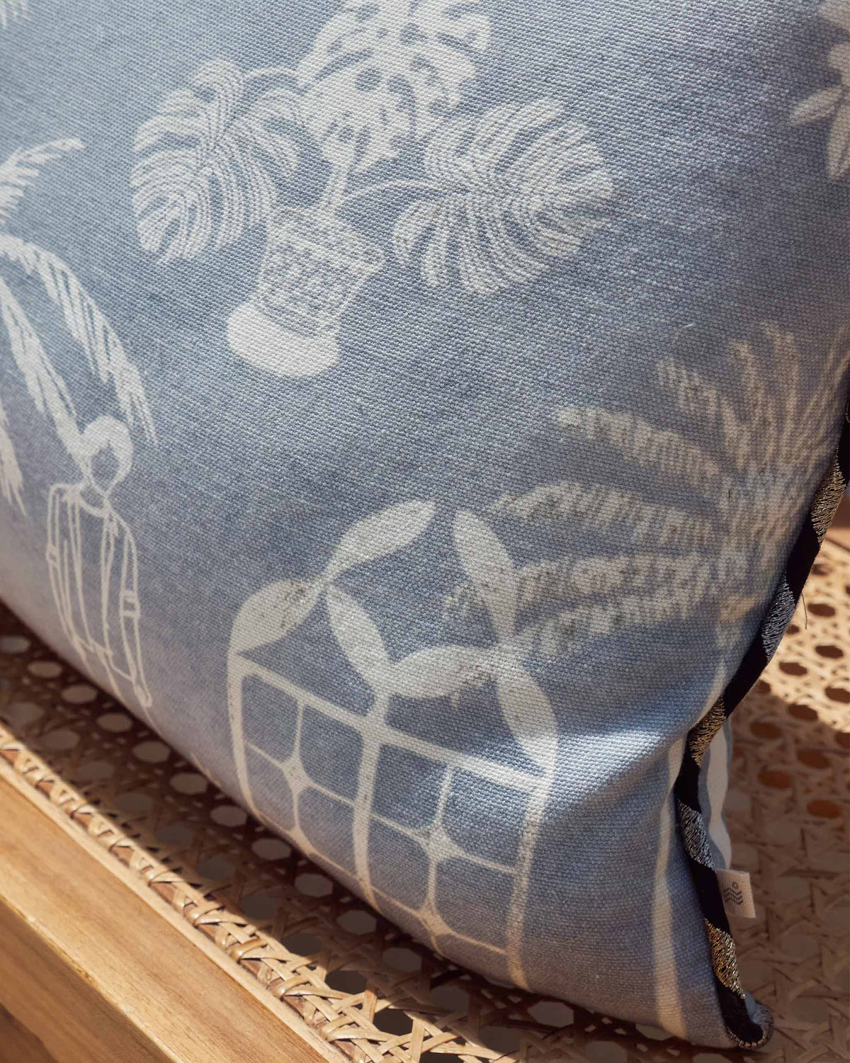 Close-up of a Coastal Evening Cushion Cover showing white palm and plant motifs.