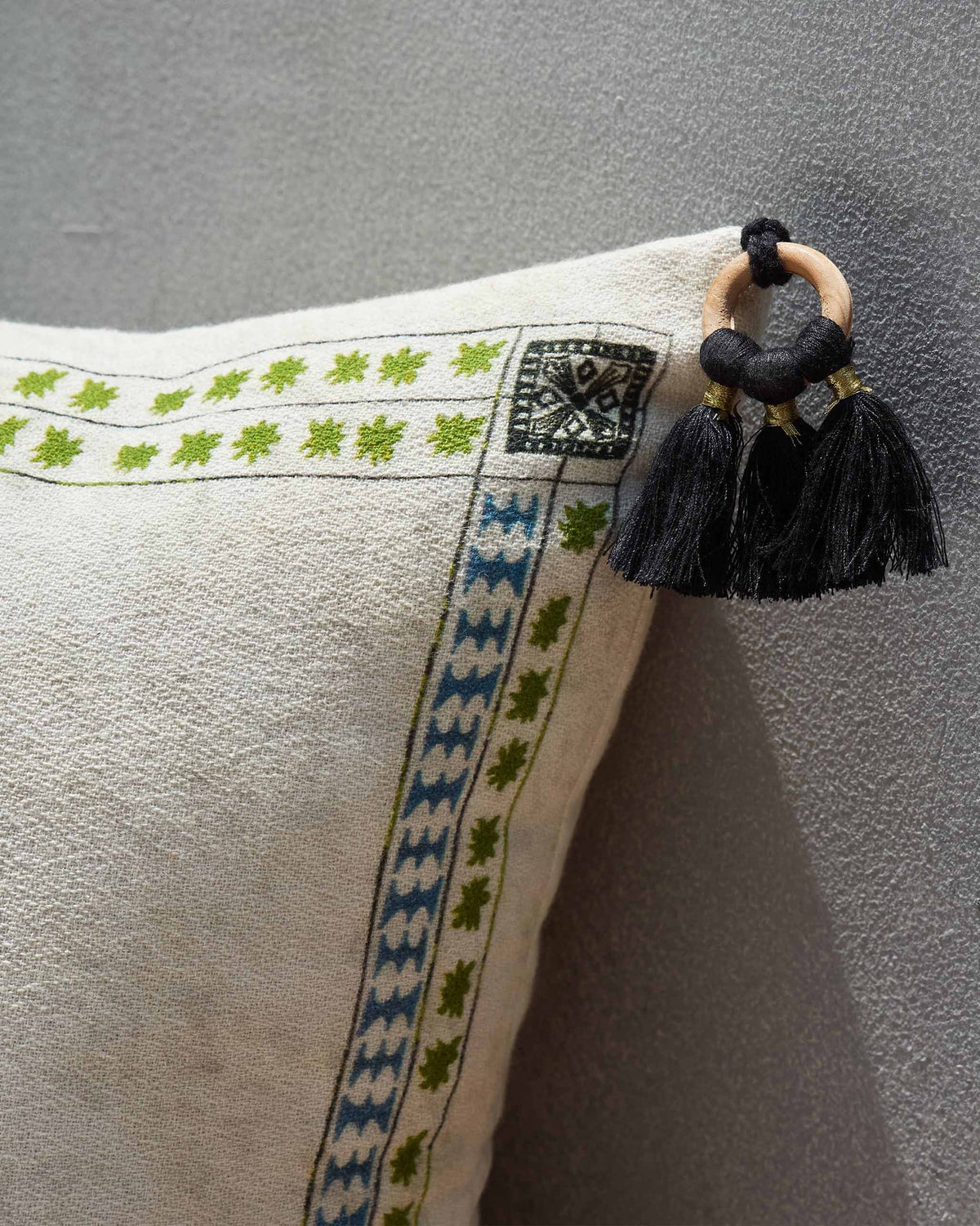 Corner of the Crab Cushion Cover showing green and blue border stitching and a black tassel.