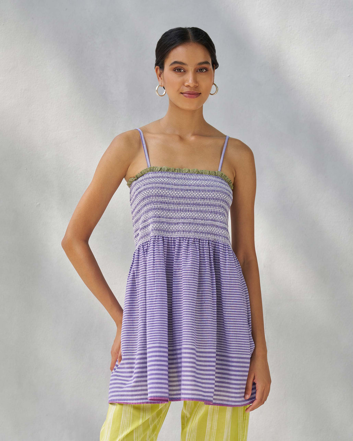Person wearing a purple and white Paradise top with a smocked bodice and thin straps.