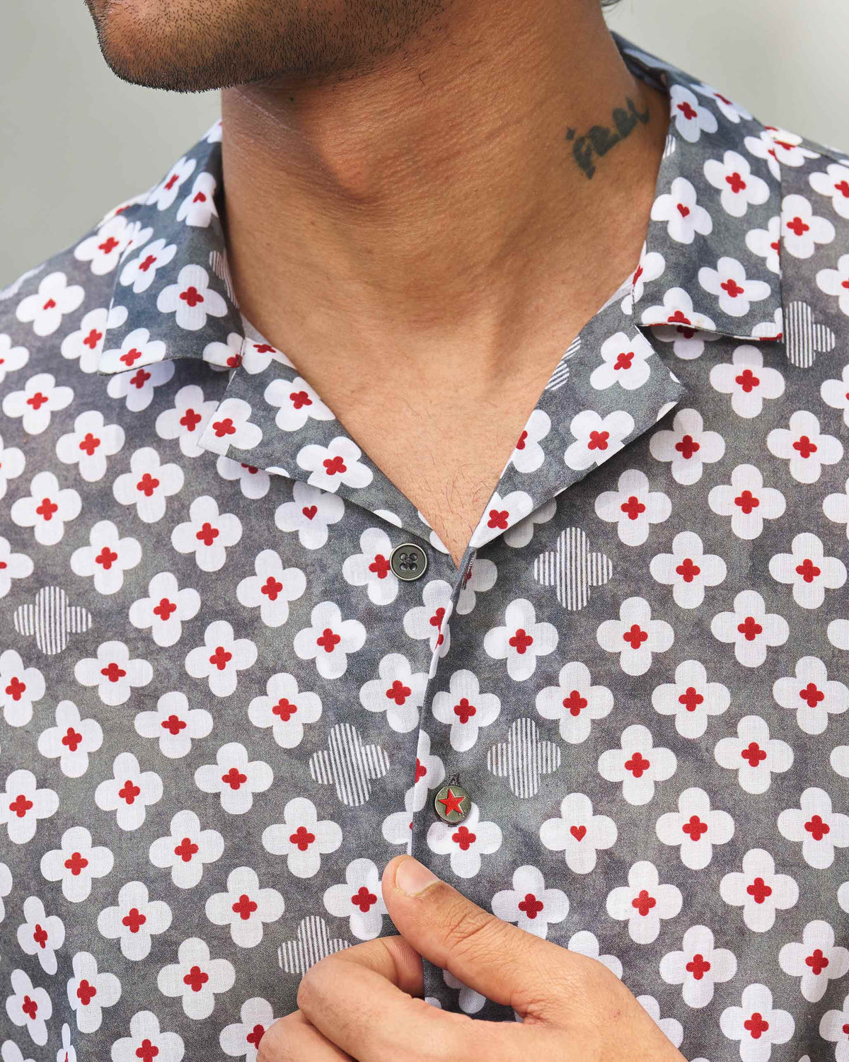 Close-up of a grey Mistari shirt placket showing a red star button.