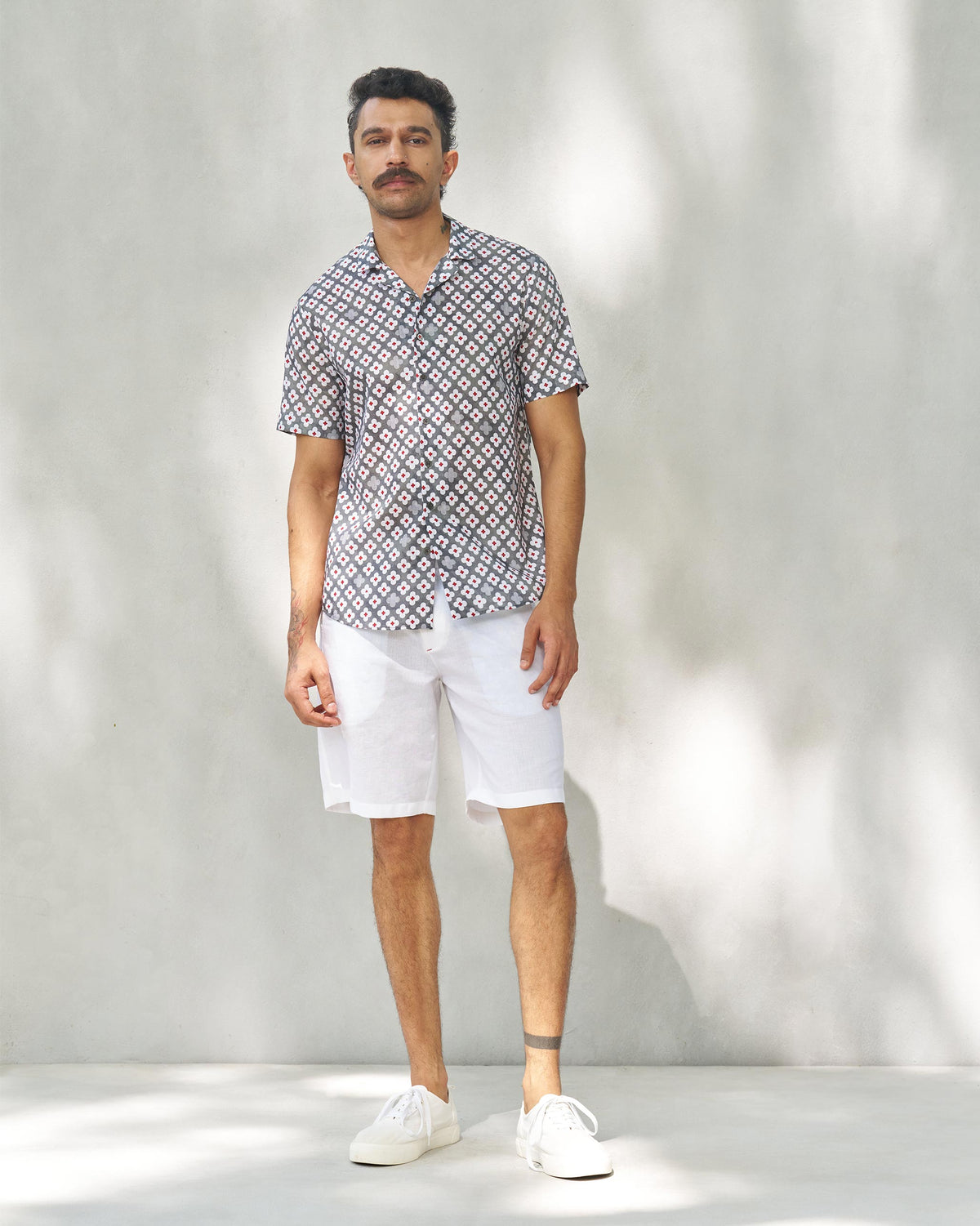 Person wearing a grey Mistari shirt with a white and red print, shown head to toe.