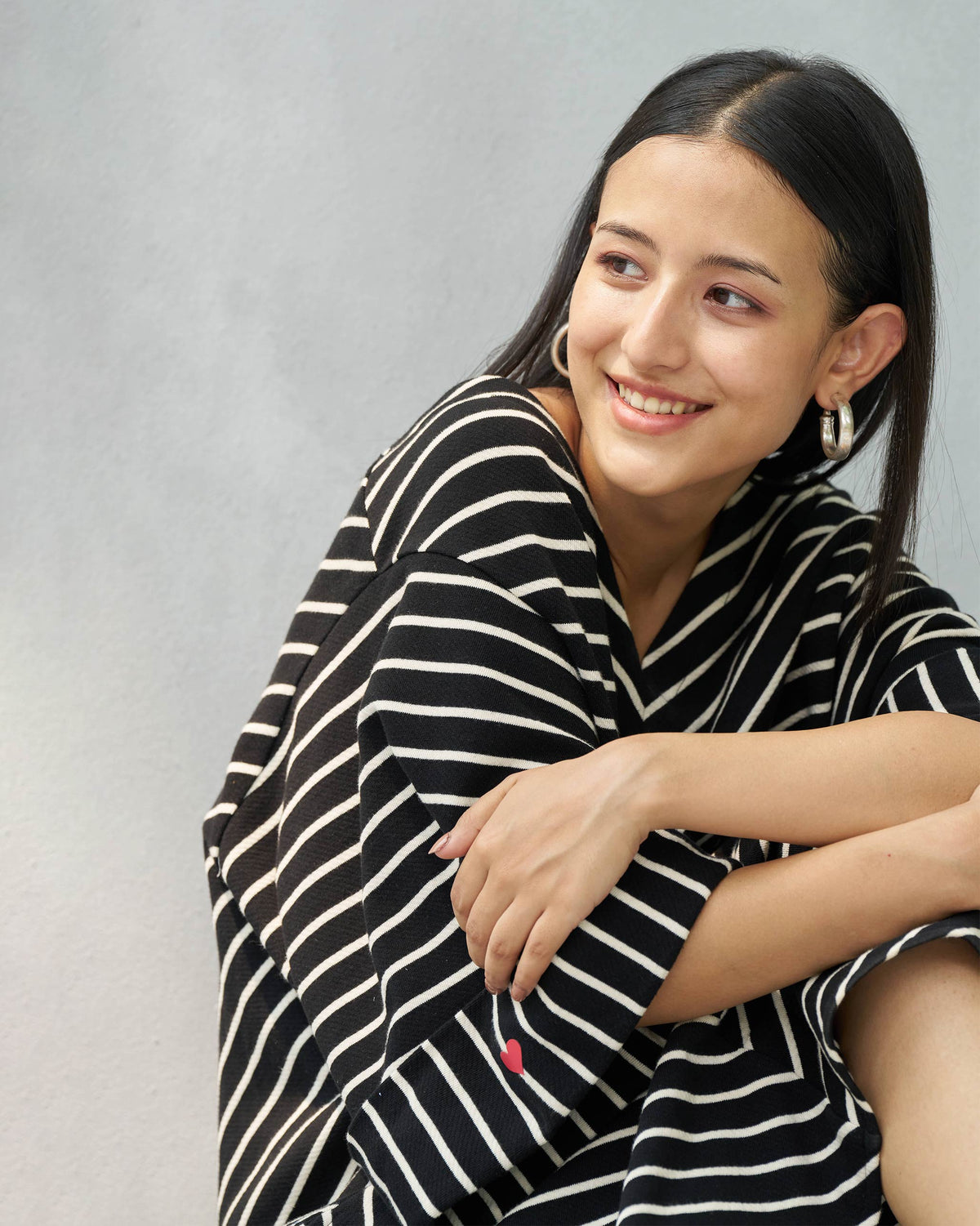 Person seated wearing an Amelia kaftan in black and beige stripes.