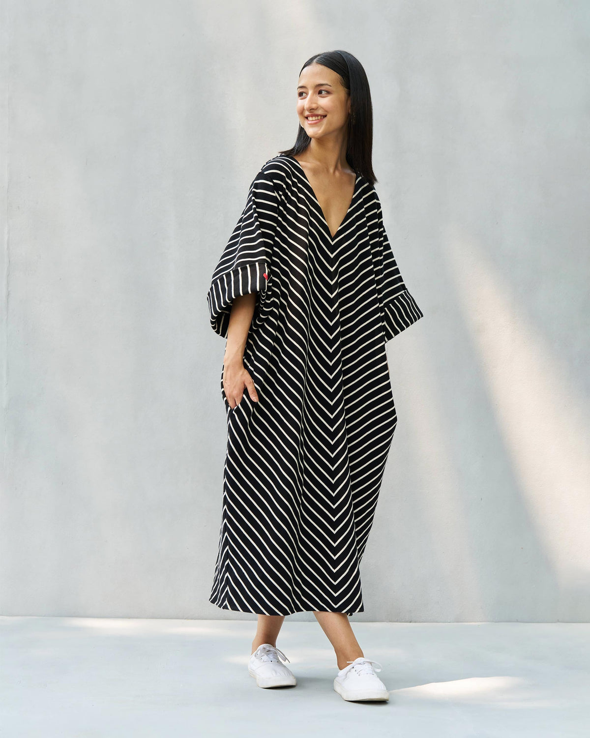 Person wearing an Amelia kaftan in black and beige chevron stripes, shown full length.