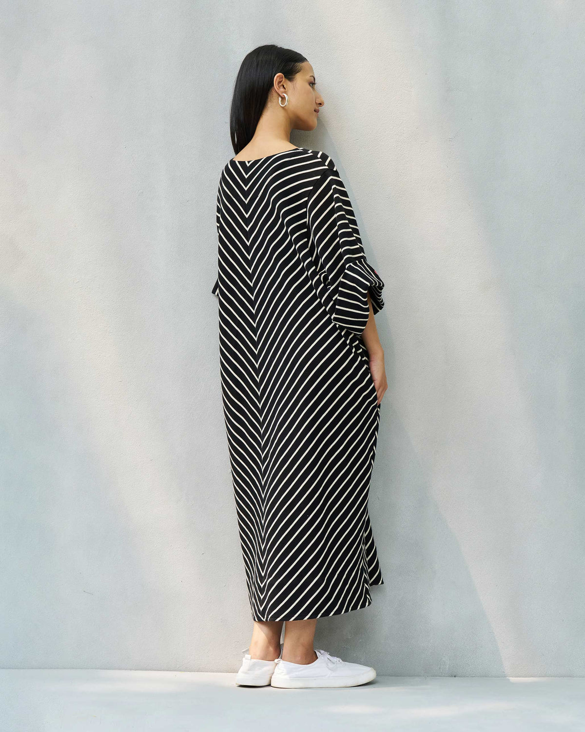 Back of an Amelia kaftan worn by a person, in black and beige chevron stripes.