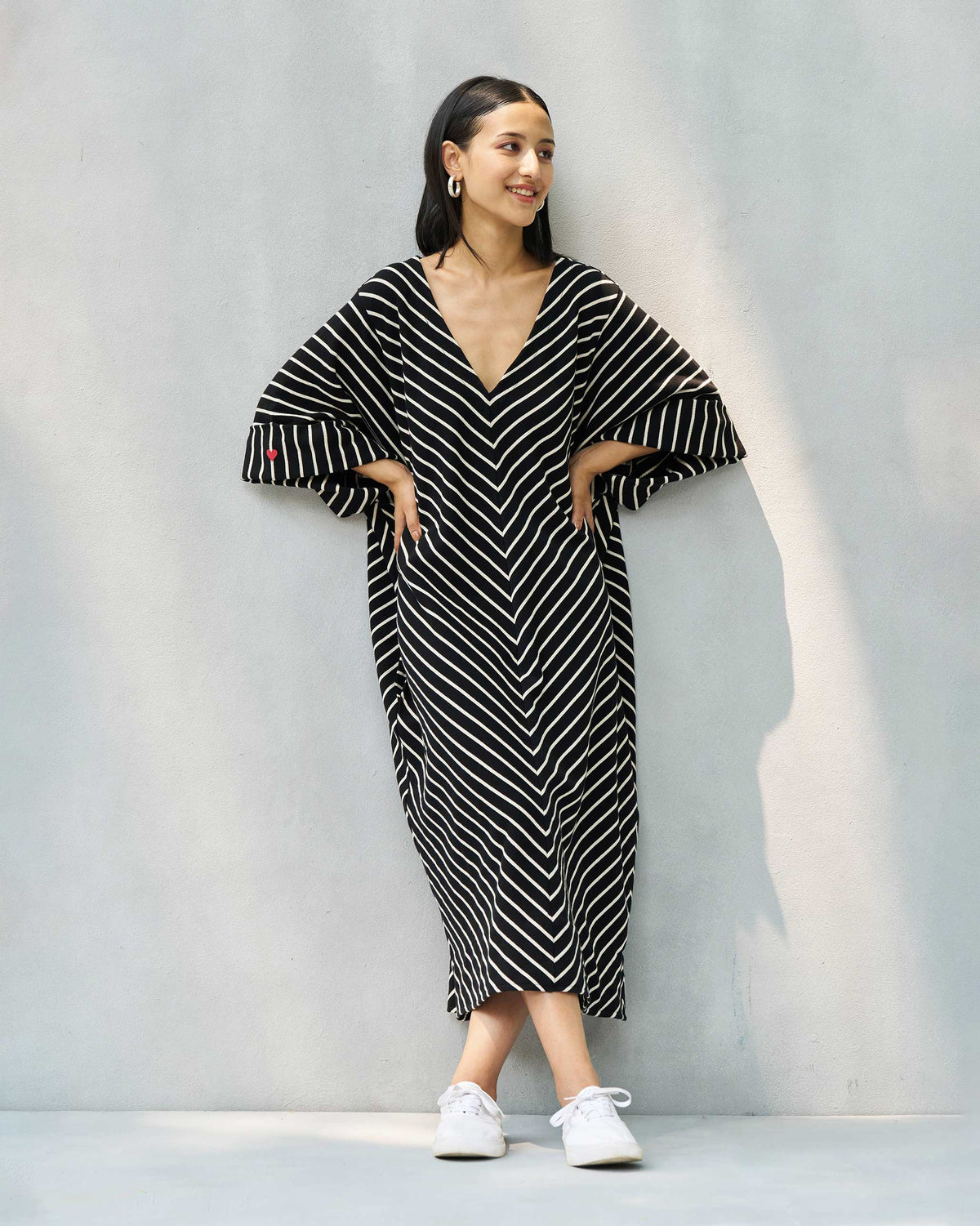 Person wearing an Amelia kaftan with wide sleeves and a red heart on the cuff.