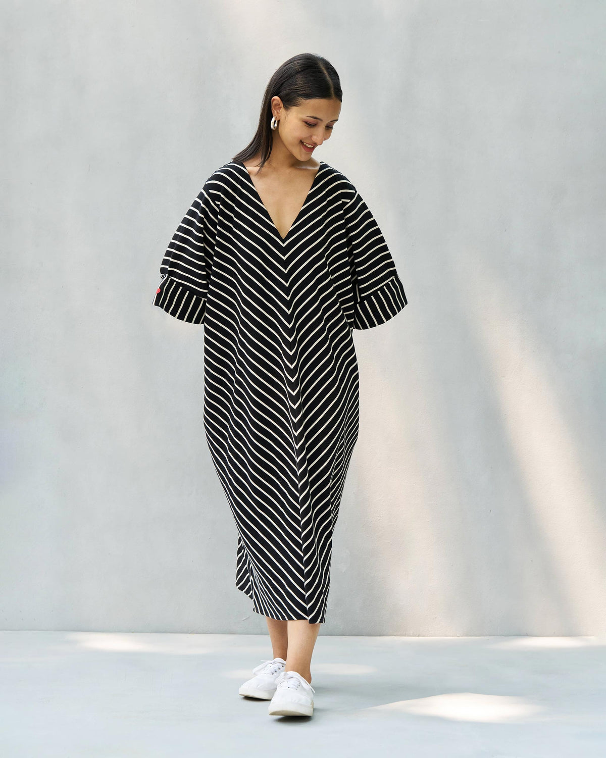 Person wearing an Amelia kaftan in black and beige chevron stripes, looking down.