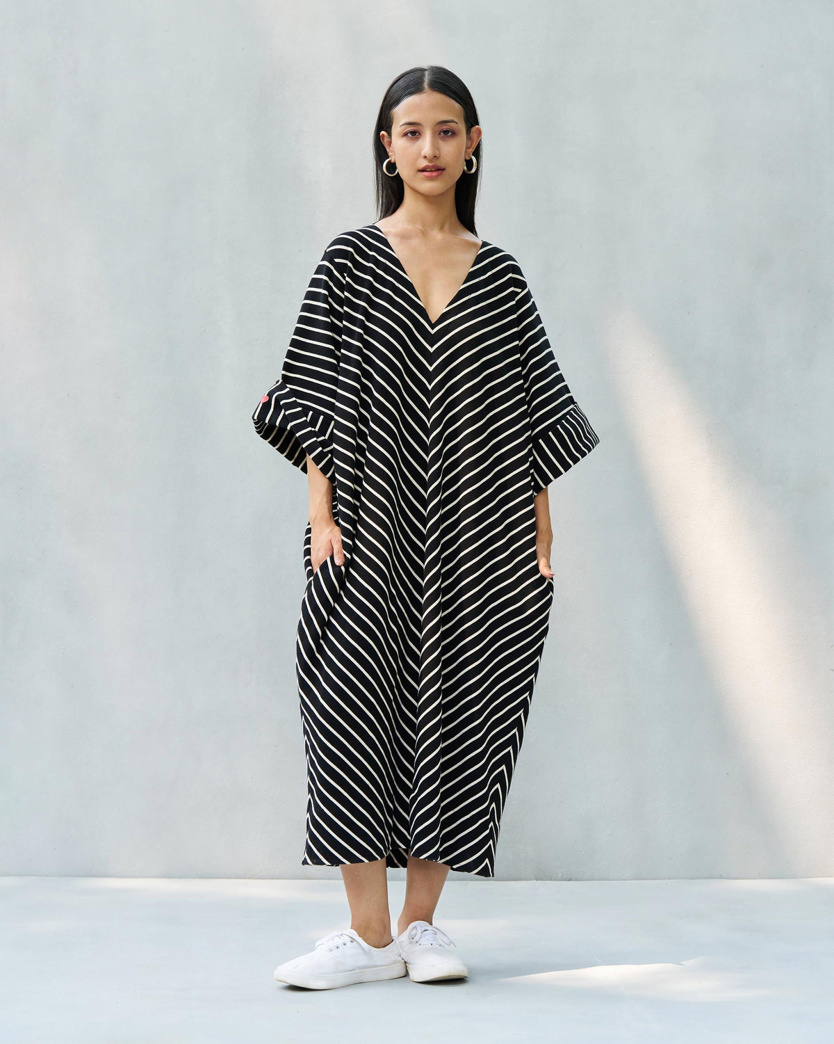 Person wearing an Amelia kaftan with wide striped sleeves, shown full length.