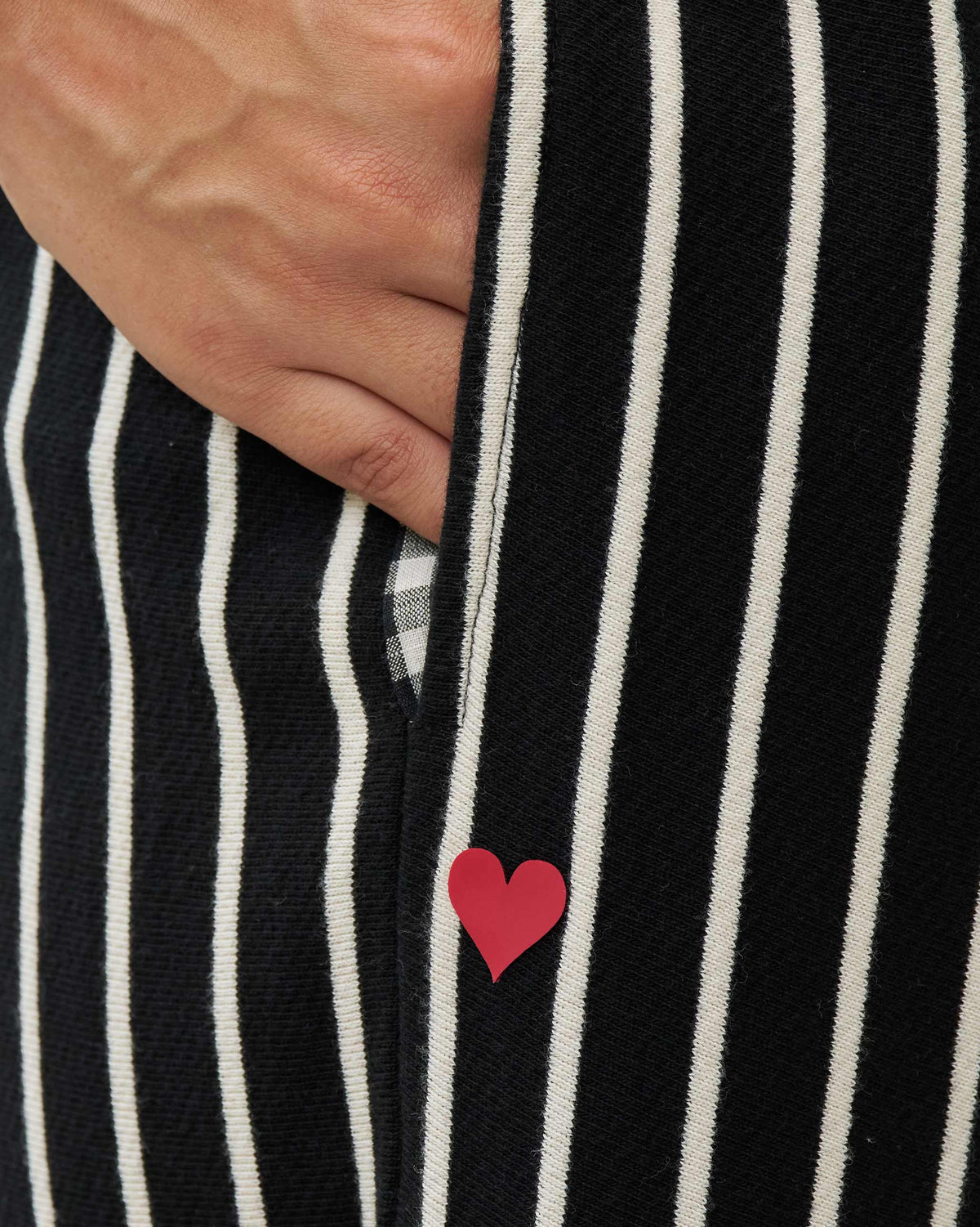 Close-up of black and beige striped Nova pants with a red heart on the leg.