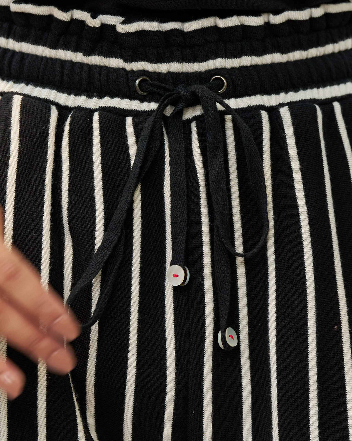 Close-up of the drawstring waist on black and beige striped Nova pants.