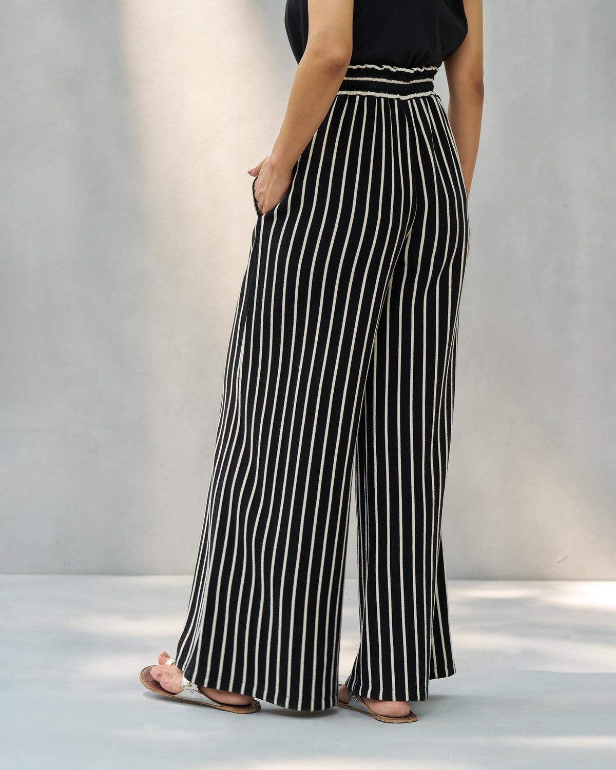 Back of black and beige striped Nova pants with a wide leg worn by a person.