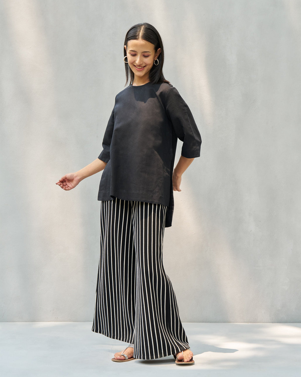 Person wearing black and beige striped Nova pants with a wide leg, mid-stride.