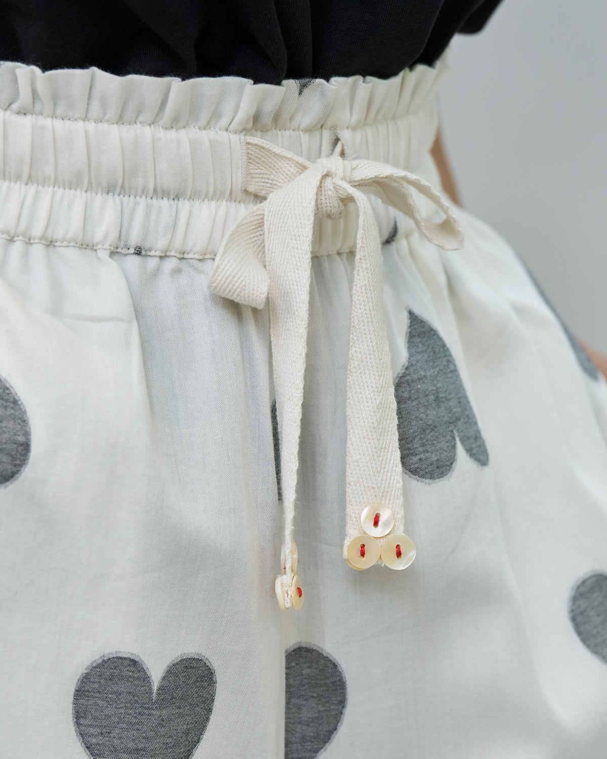 Close-up of Nova pants' drawstring waist in ivory with grey heart print.