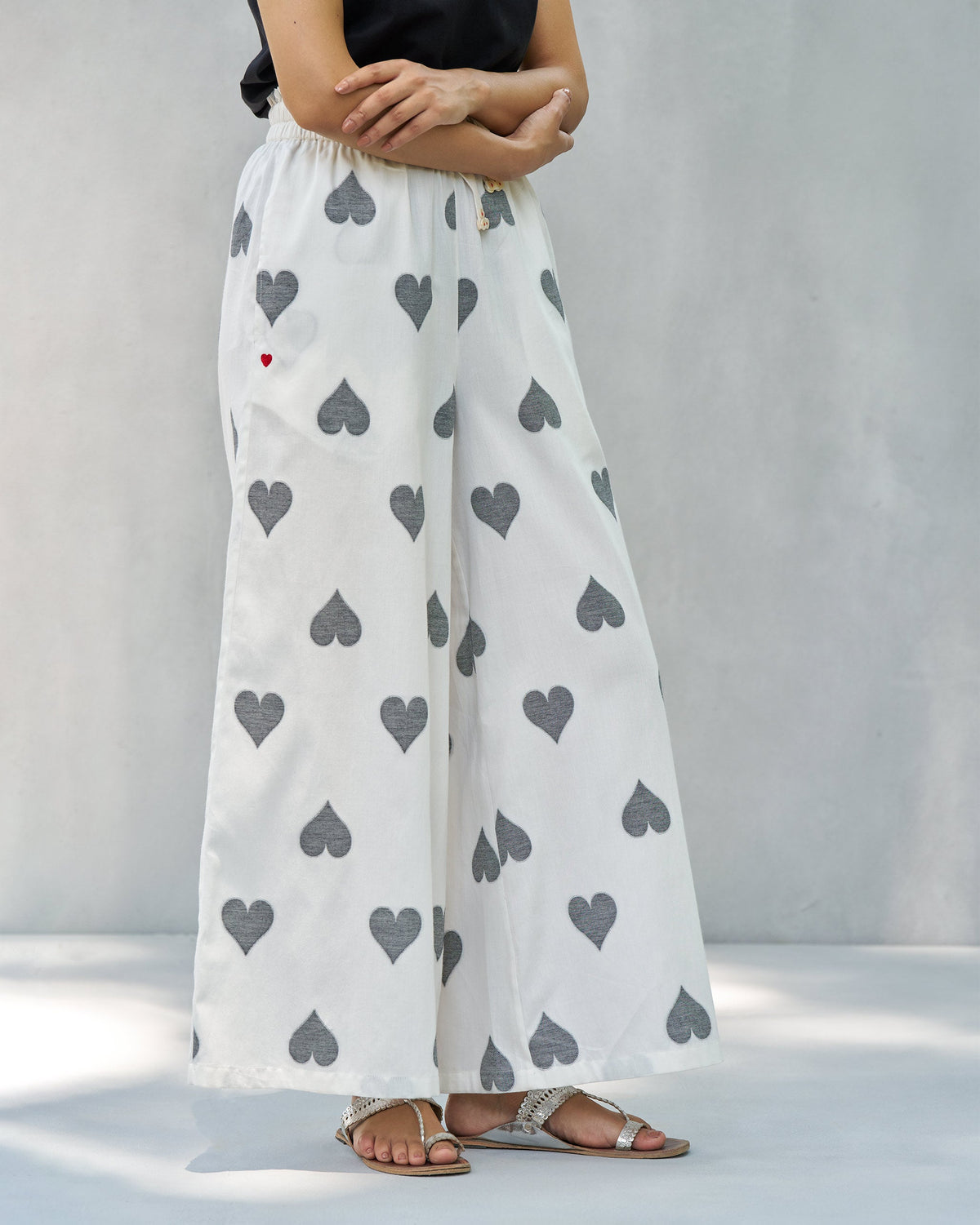 Side view of Nova pants in ivory with a wide leg and grey heart print.