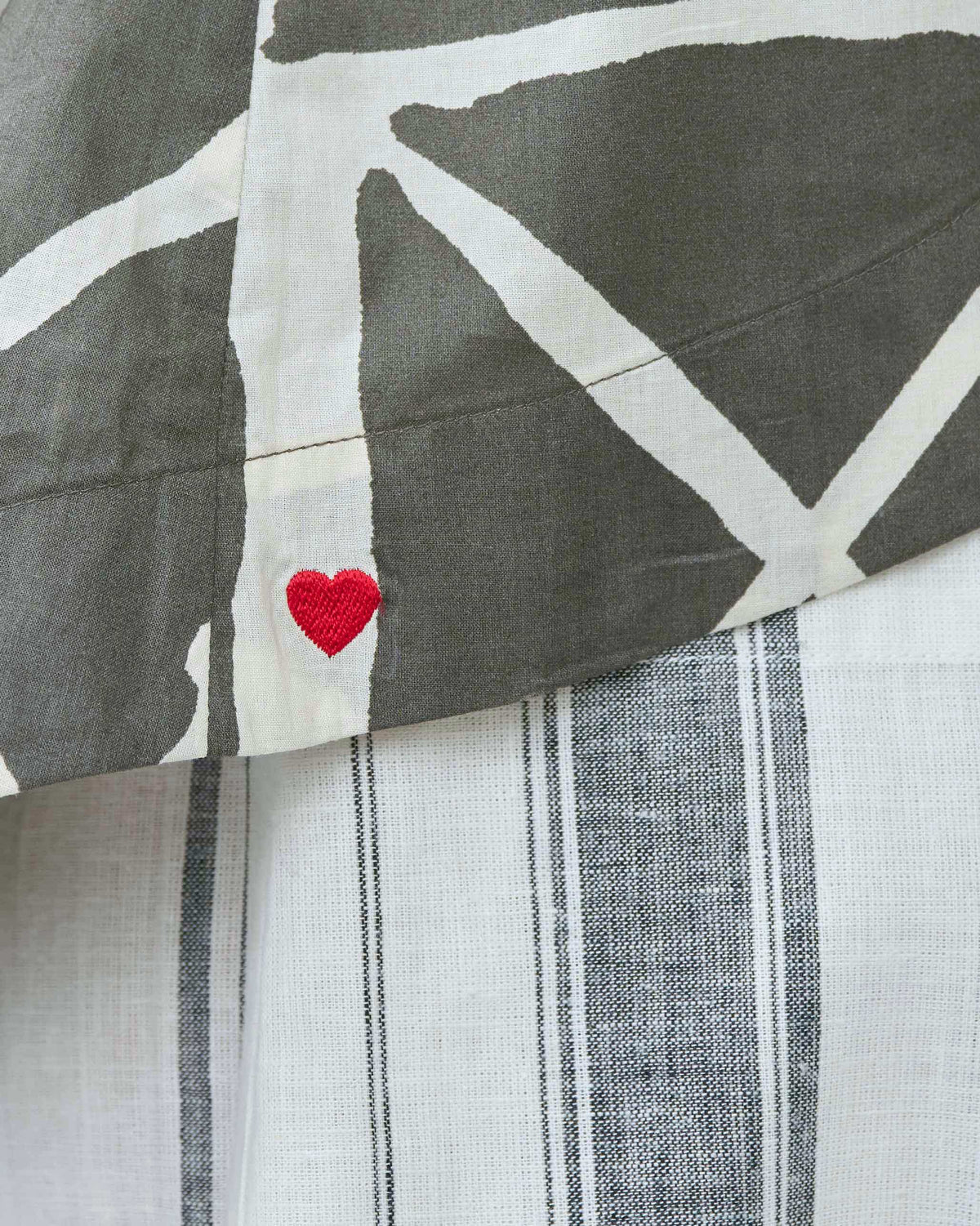 Close-up of a Gina top hem showing a small red heart embroidered on the side.