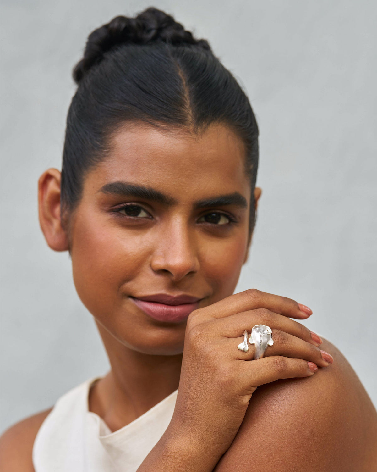 Person wearing a silver Mud-Fish ring, hand resting near the shoulder.