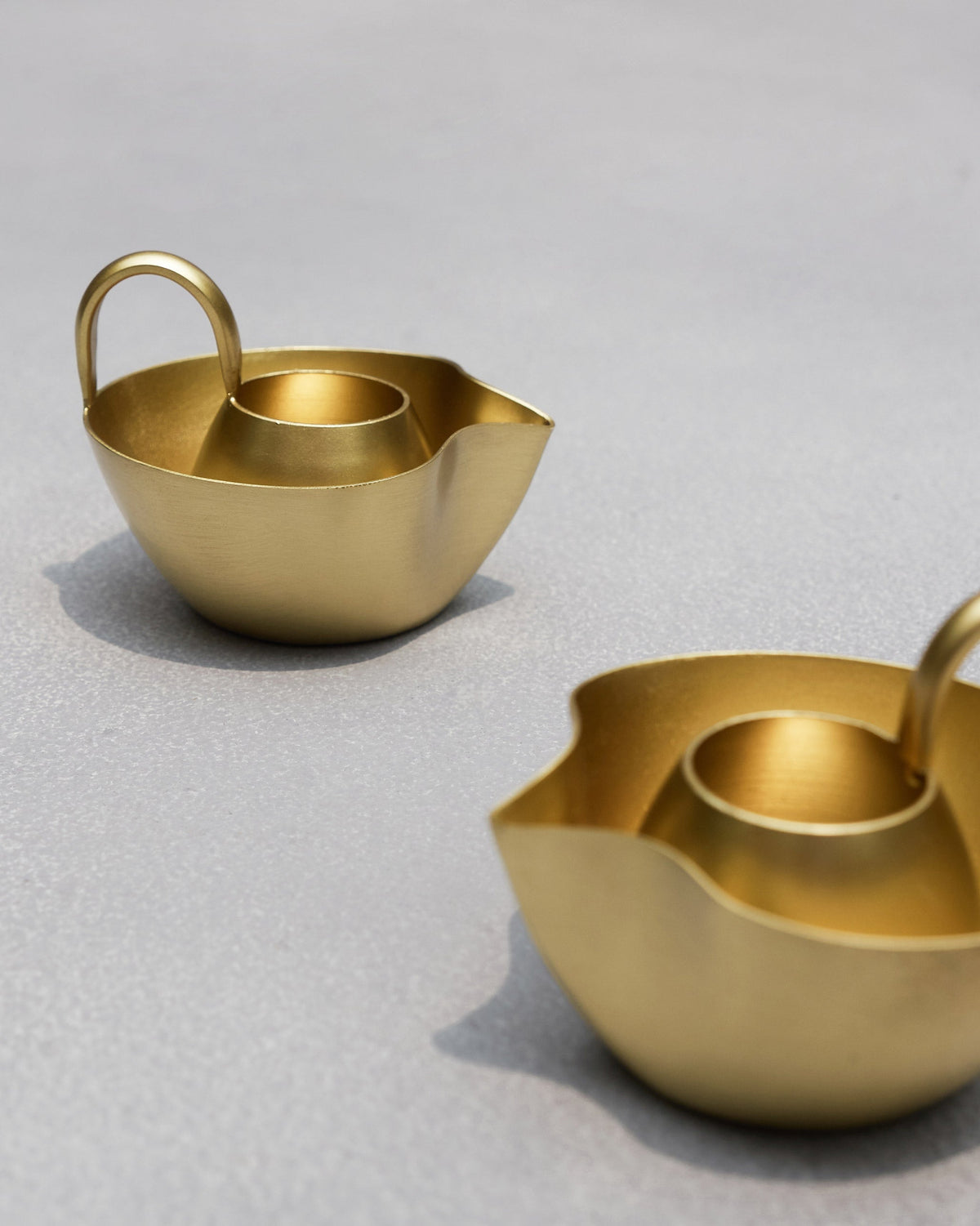 Asfar Diya with a gold handle and deep cup, the second diya at the edge.