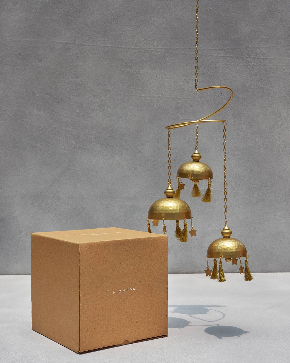 Asfar Windchime hanging beside a plain kraft box.
