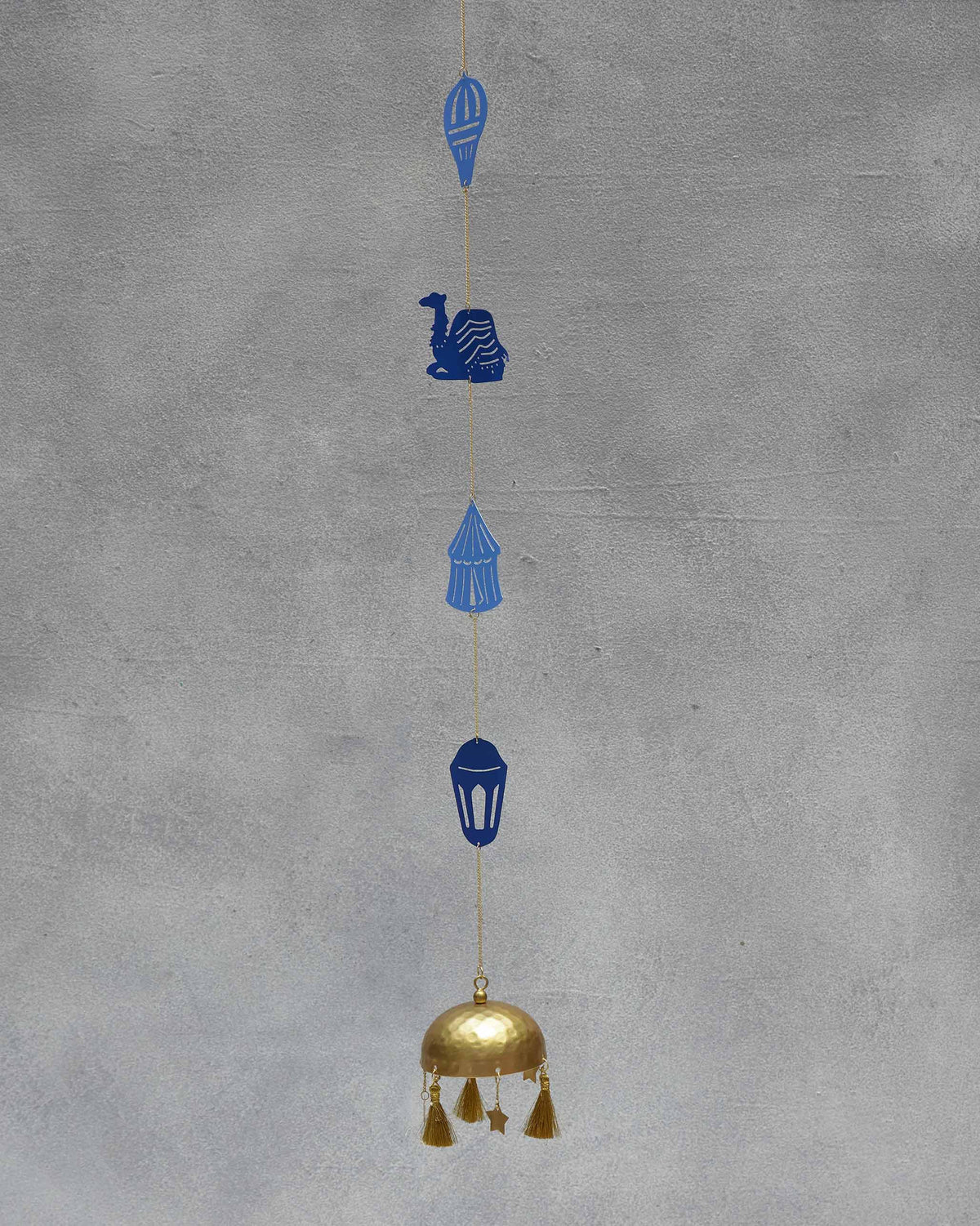 Azraq Toran hanging on a grey wall, its blue camel motif near the top.