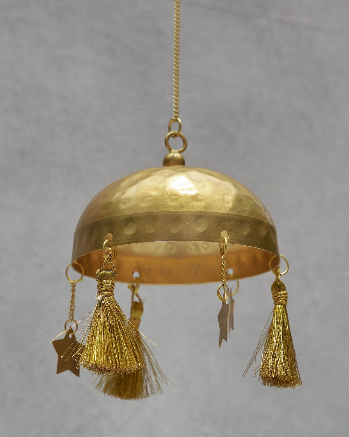 Close-up of the Azraq Toran's brass bell with tassels and star charms.