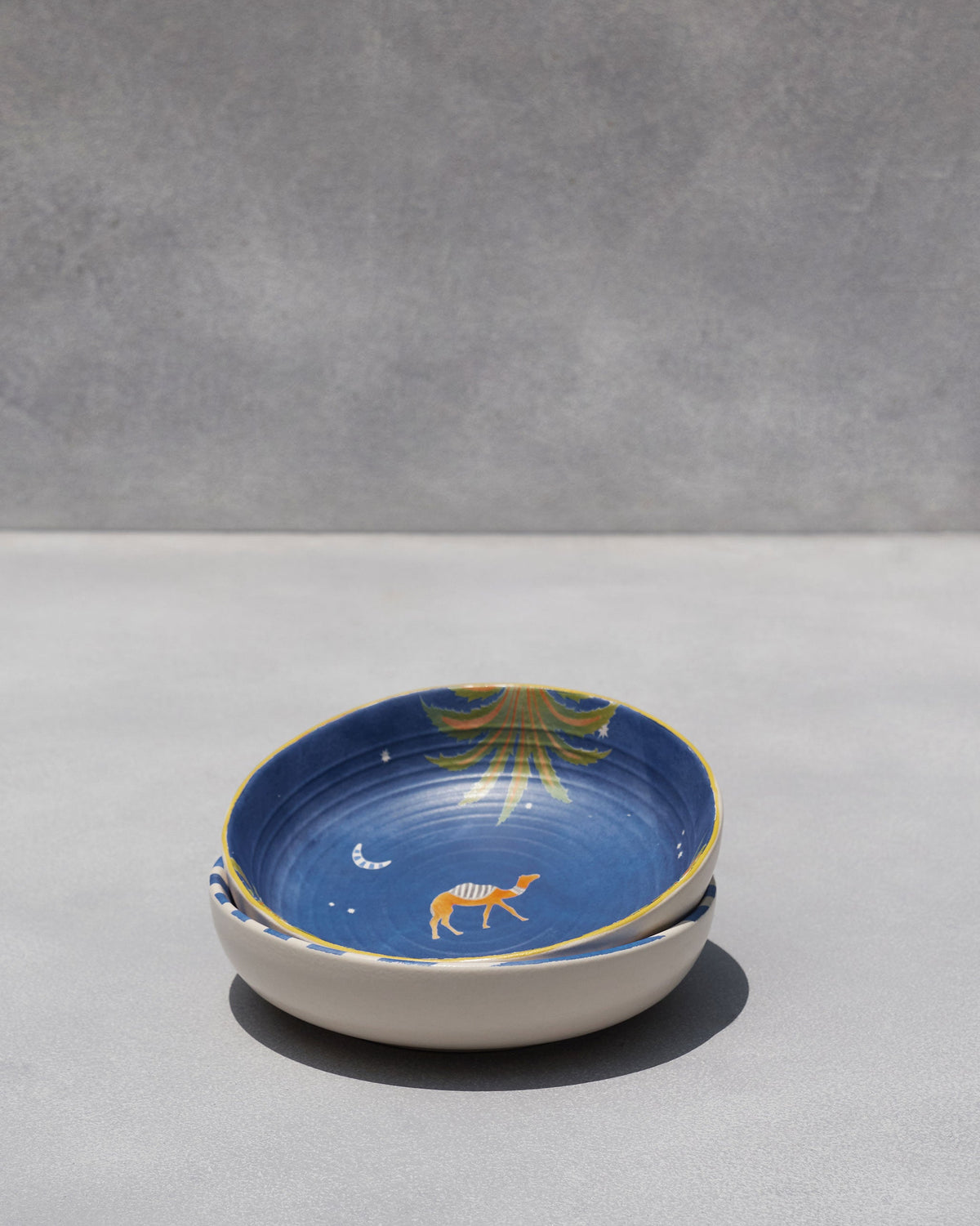 Sahara shallow bowl with camel, moon and palm motifs on a deep blue interior.